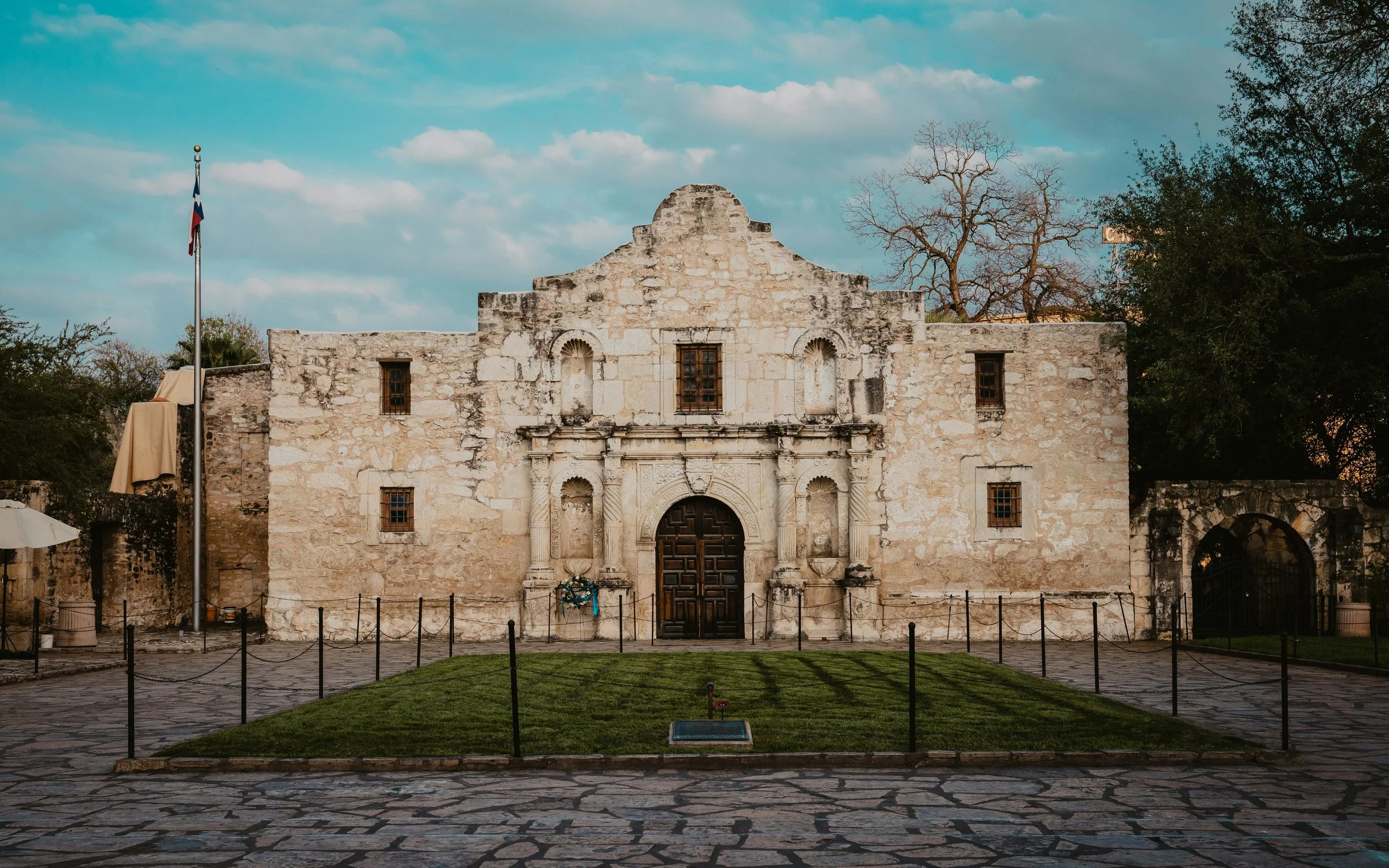 The Alamo in San Antonio is a ruined church with a lawn in front and a texas flag flying. Drives & Detours Best places to eat in San Antonio