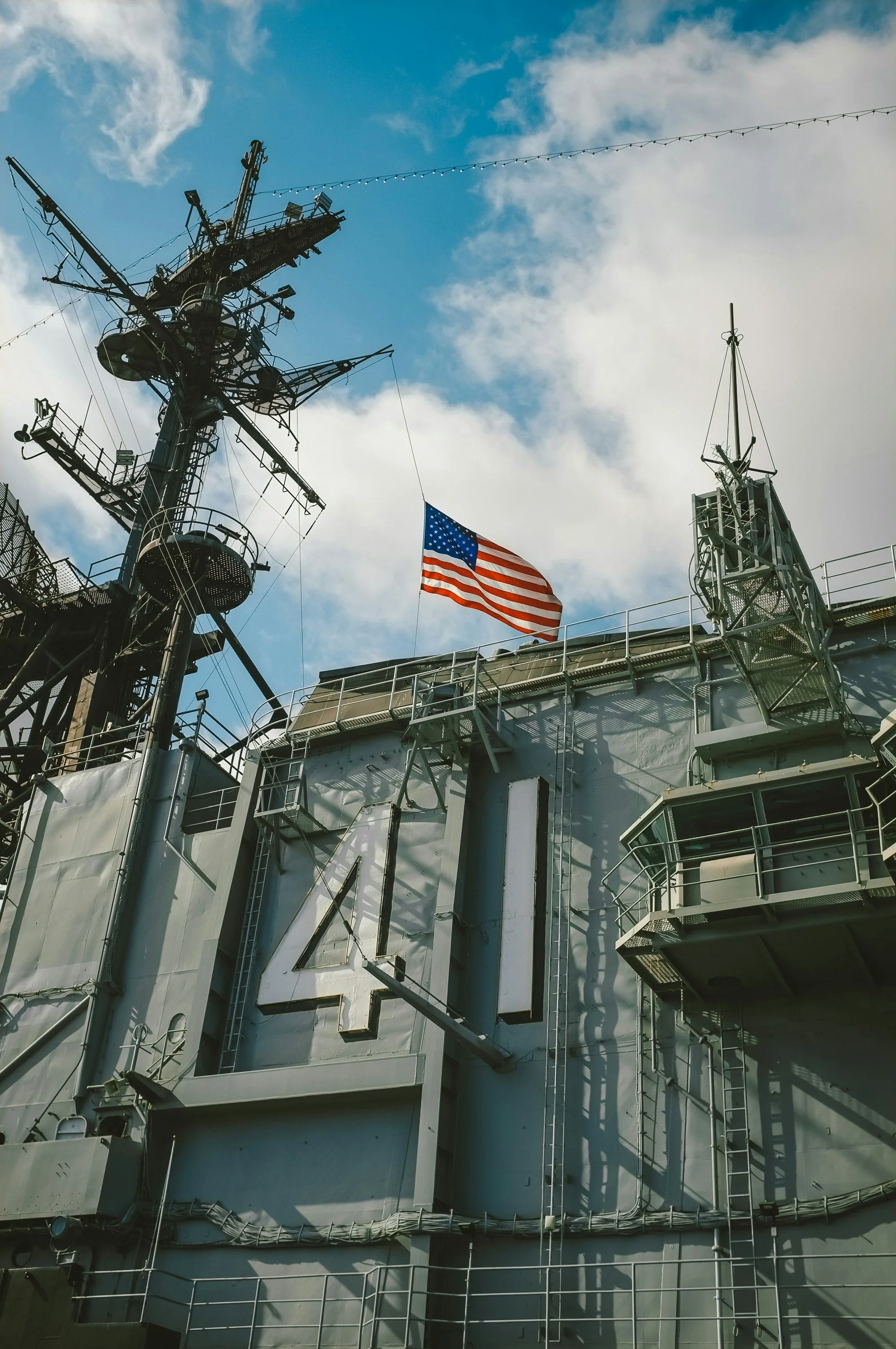 An American flag flies above the bridge of an aircraft carrier. Drives & Detours USS Midway Museum and Embarcadero Self-Guided Tour