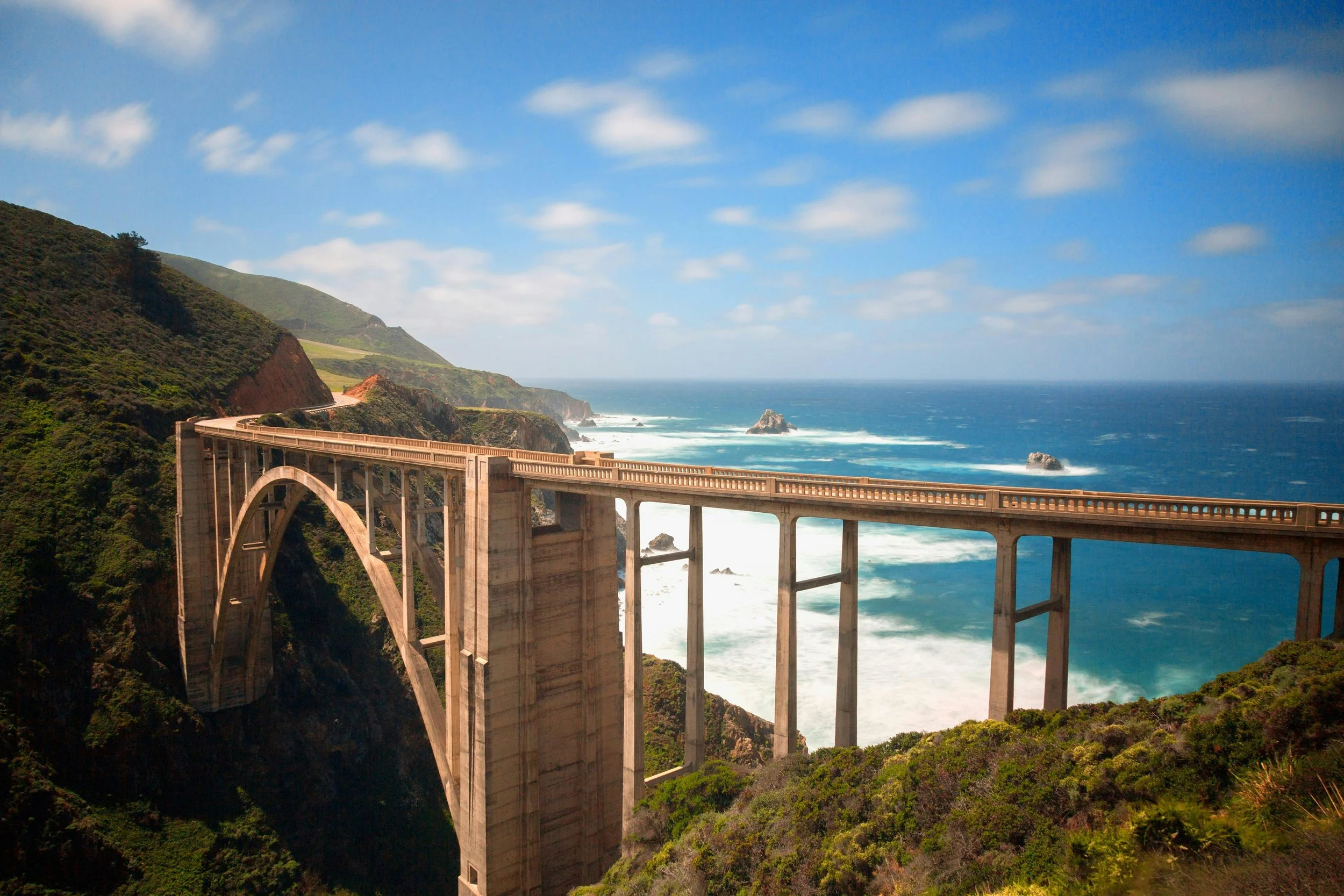 The Bixby Bridge crosses a creek on the Big Sur Coast of California near Monterey. The sea is a bright blue