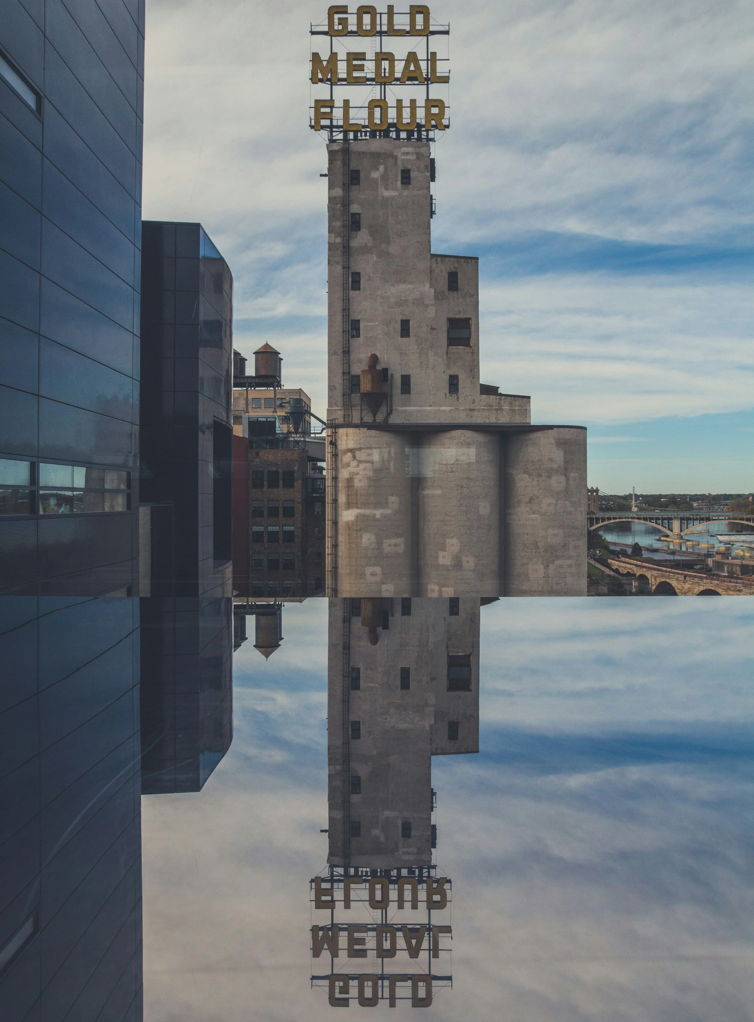 The Gold Medal Flour sign is reflected in a pool of water in Mill City. Drives & Detours Minneapolis self-guided tour
