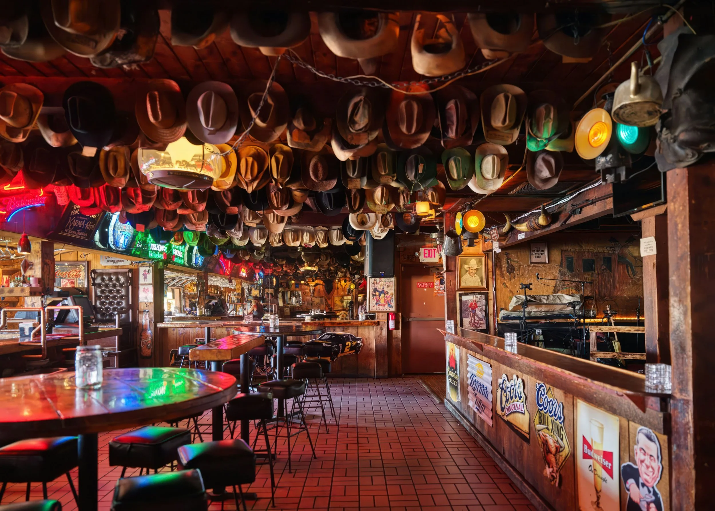 An empty bar during the day. The ceiling is covered with cowboy hats and memorabilia.