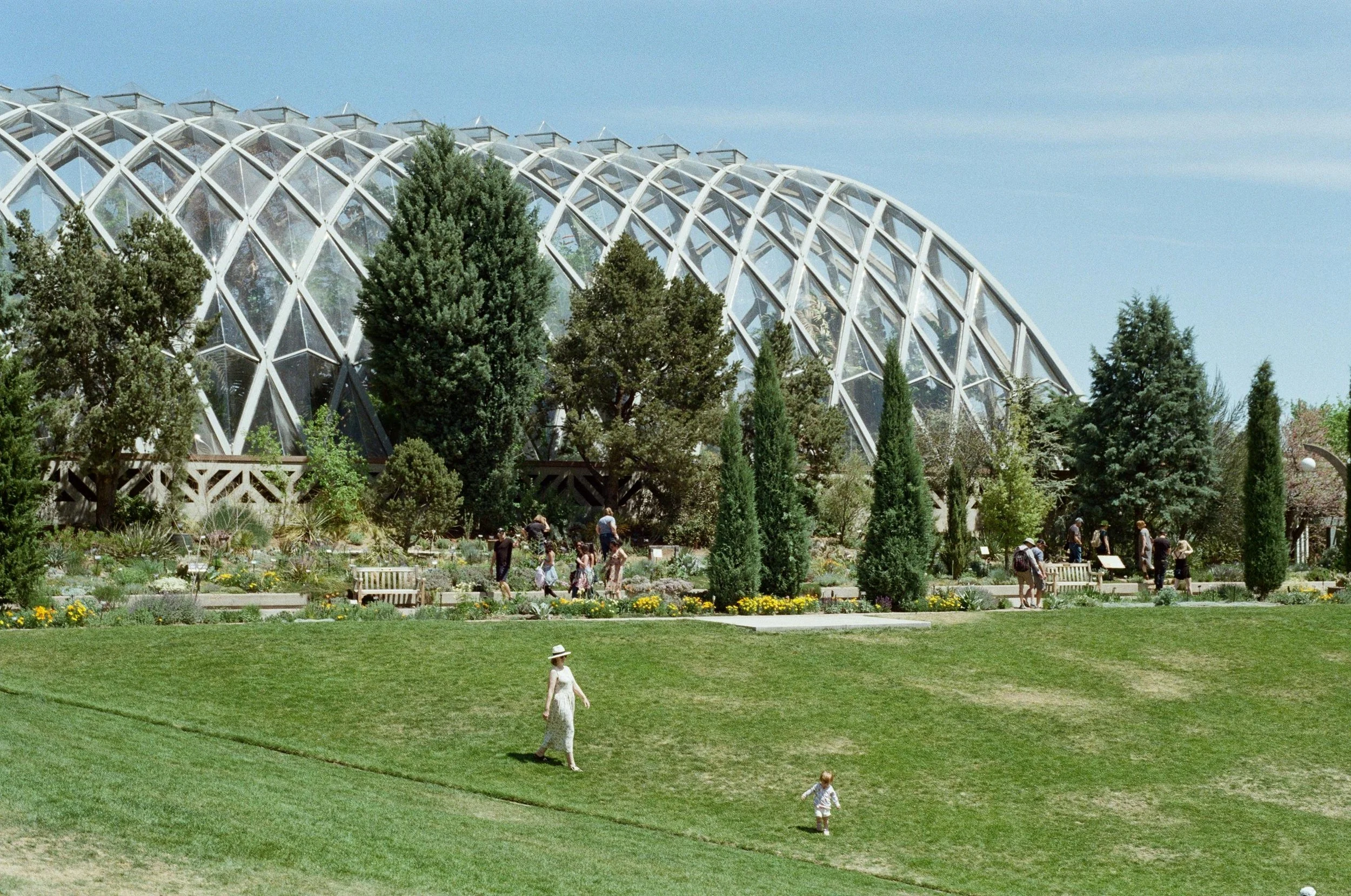 A woman and child play in the park in front of the glasshouse of a botanic gardens in Colorado. Drives & Detours Denver top attractions