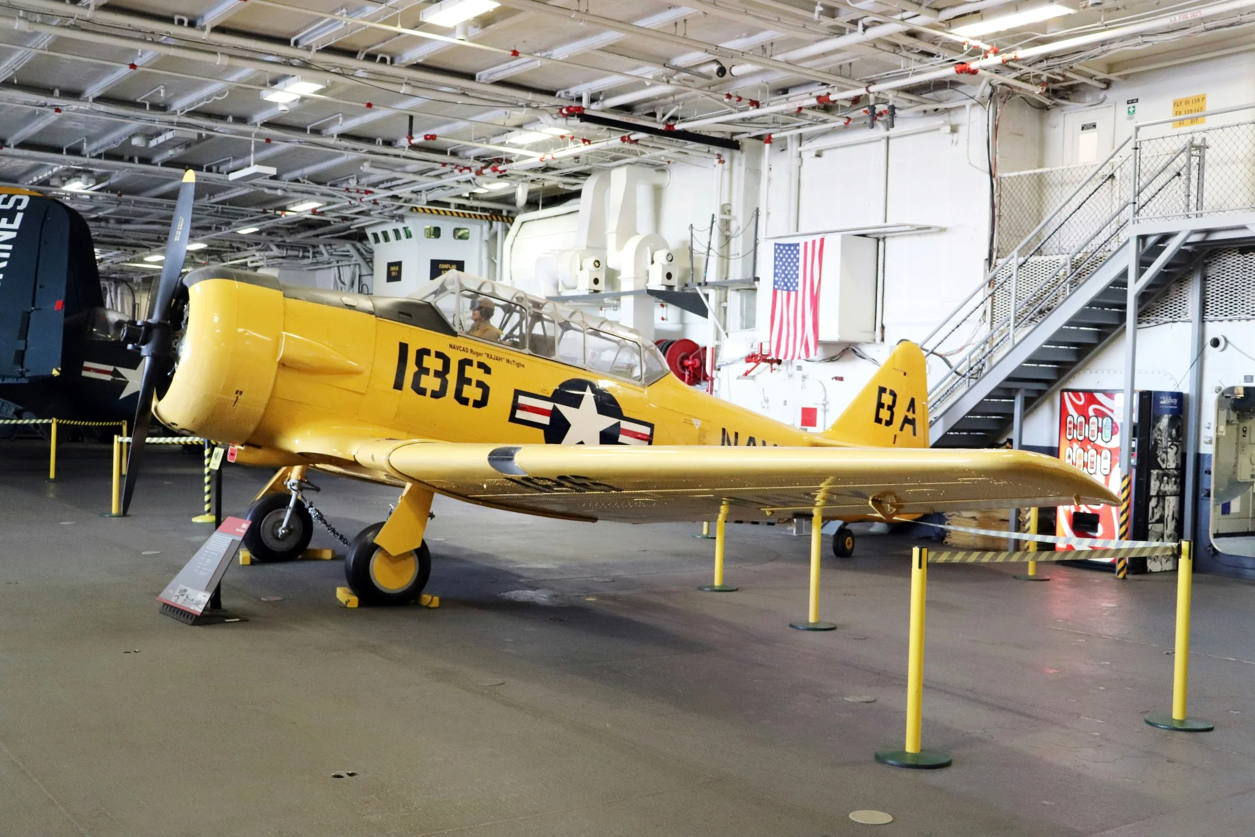 A yellow North American SNJ-6 Texan in the hold of an aircraft carrier. Drives & Detours USS Midway Museum and Embarcadero Self-Guided Tour