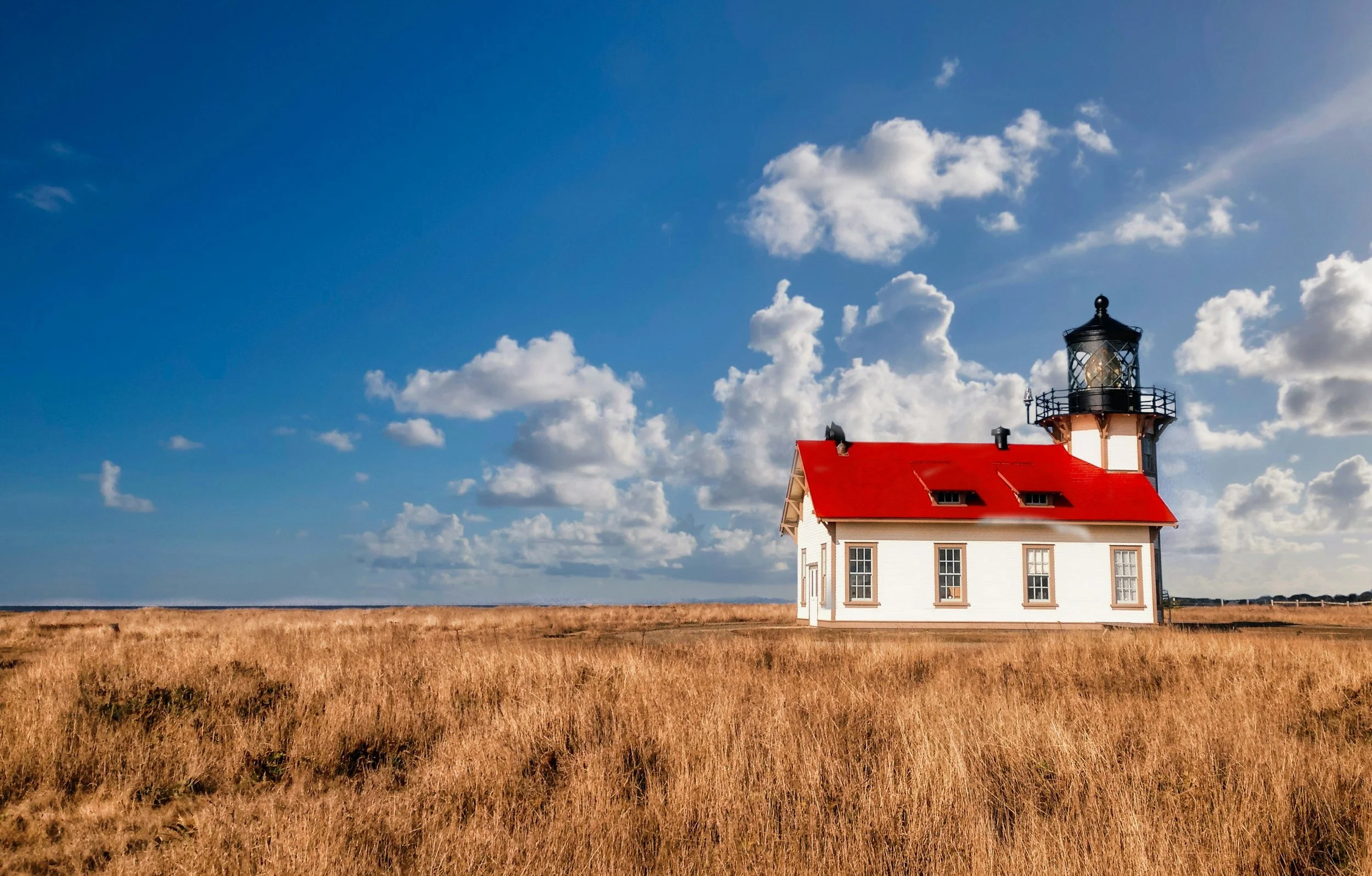 A small lighthouse in sits on the edge of the California coast under the blue sky. It has a red roof and white walls. Drives & Detours Mendocino walking tour