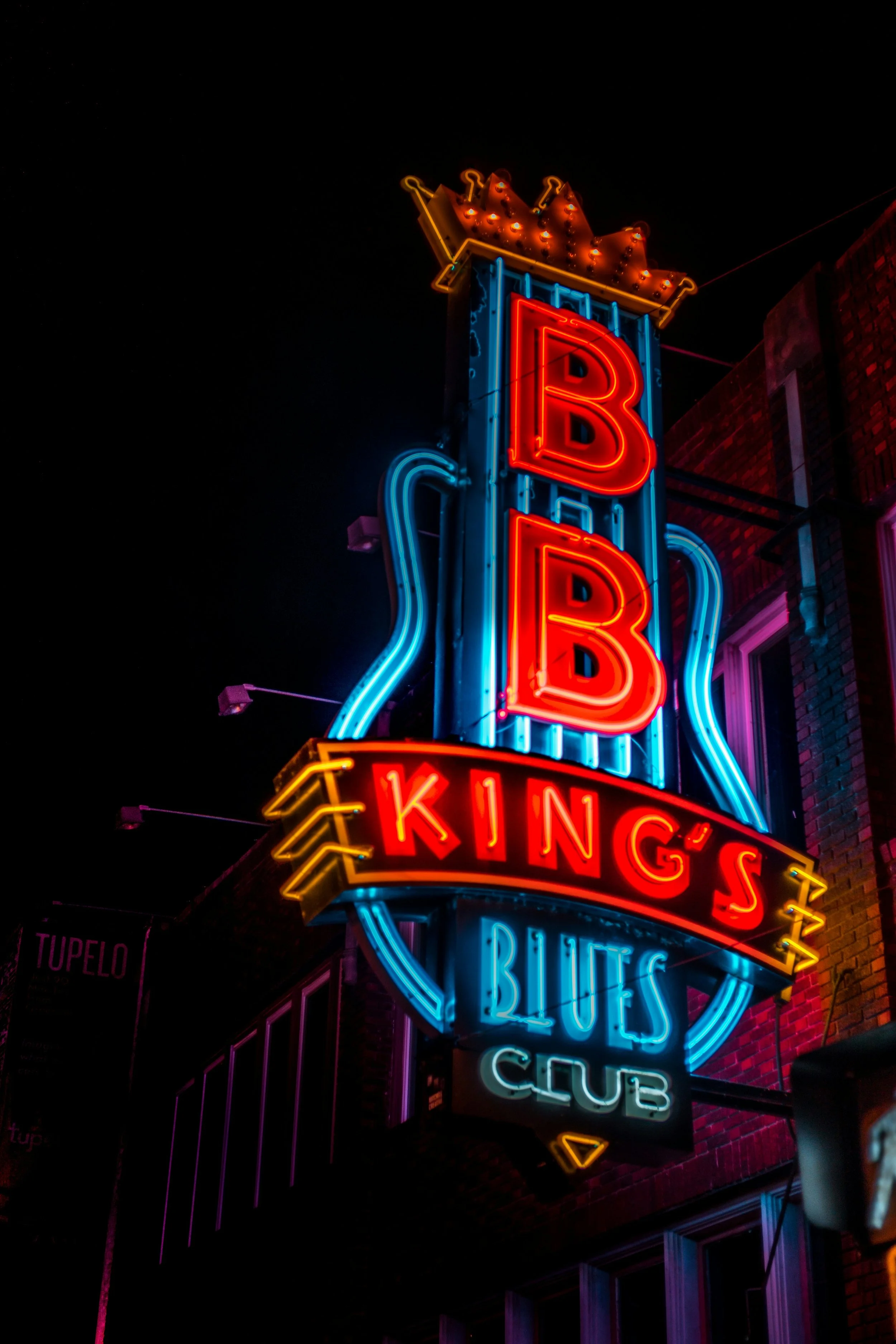 A neon sign in the shape of a guitar reads, BB King's Blues Club. Drives & Detours Memphis walking tour