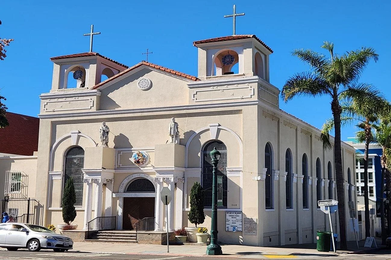 Our Lady of the Rosary church in Little Italy, San Diego. It is built in an Italian style with two small steeples. Two statues stand over the door on large plinths