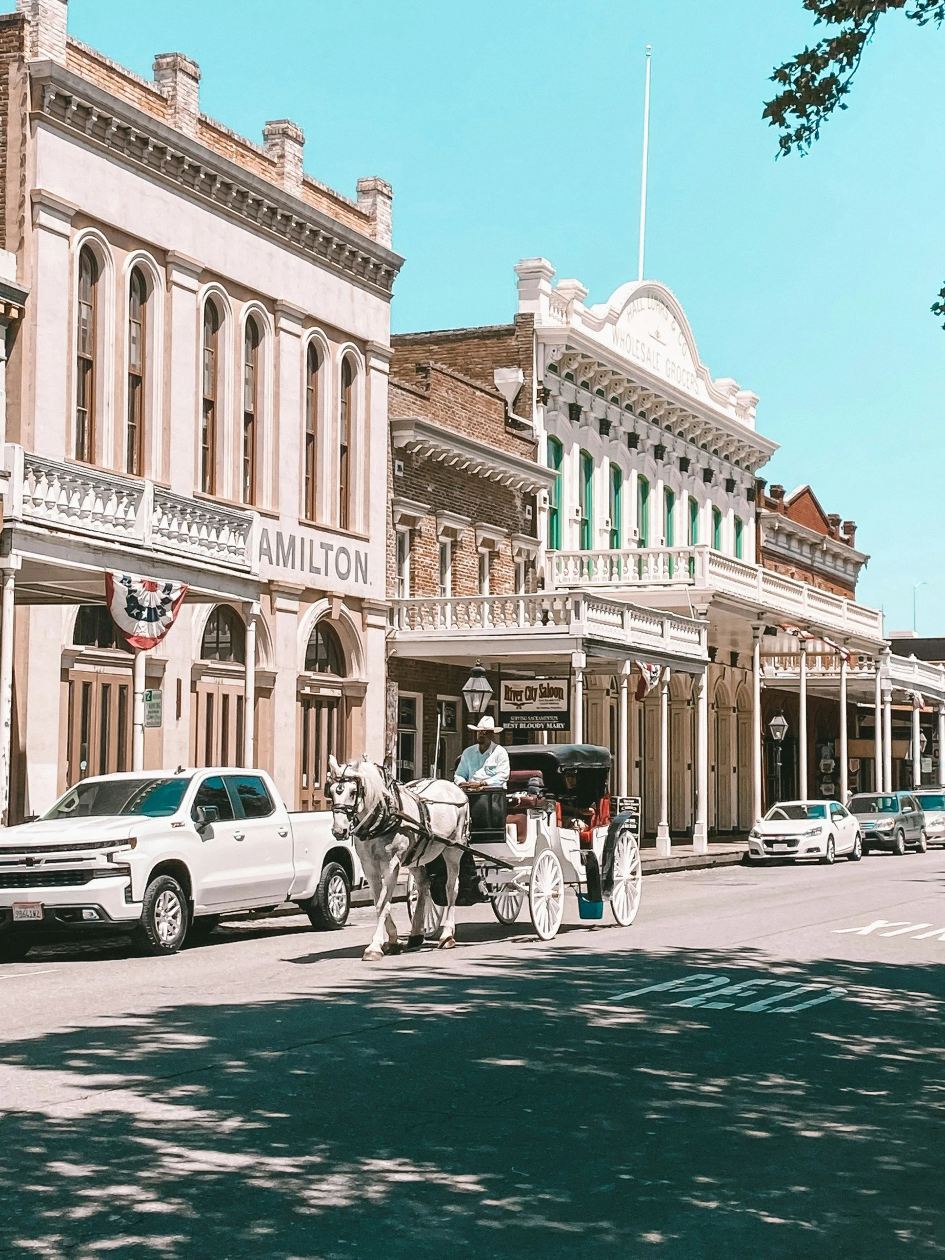 A man drives a horse and cart down a street in Old Sacramento. Wild West, gold rush buildings surround him