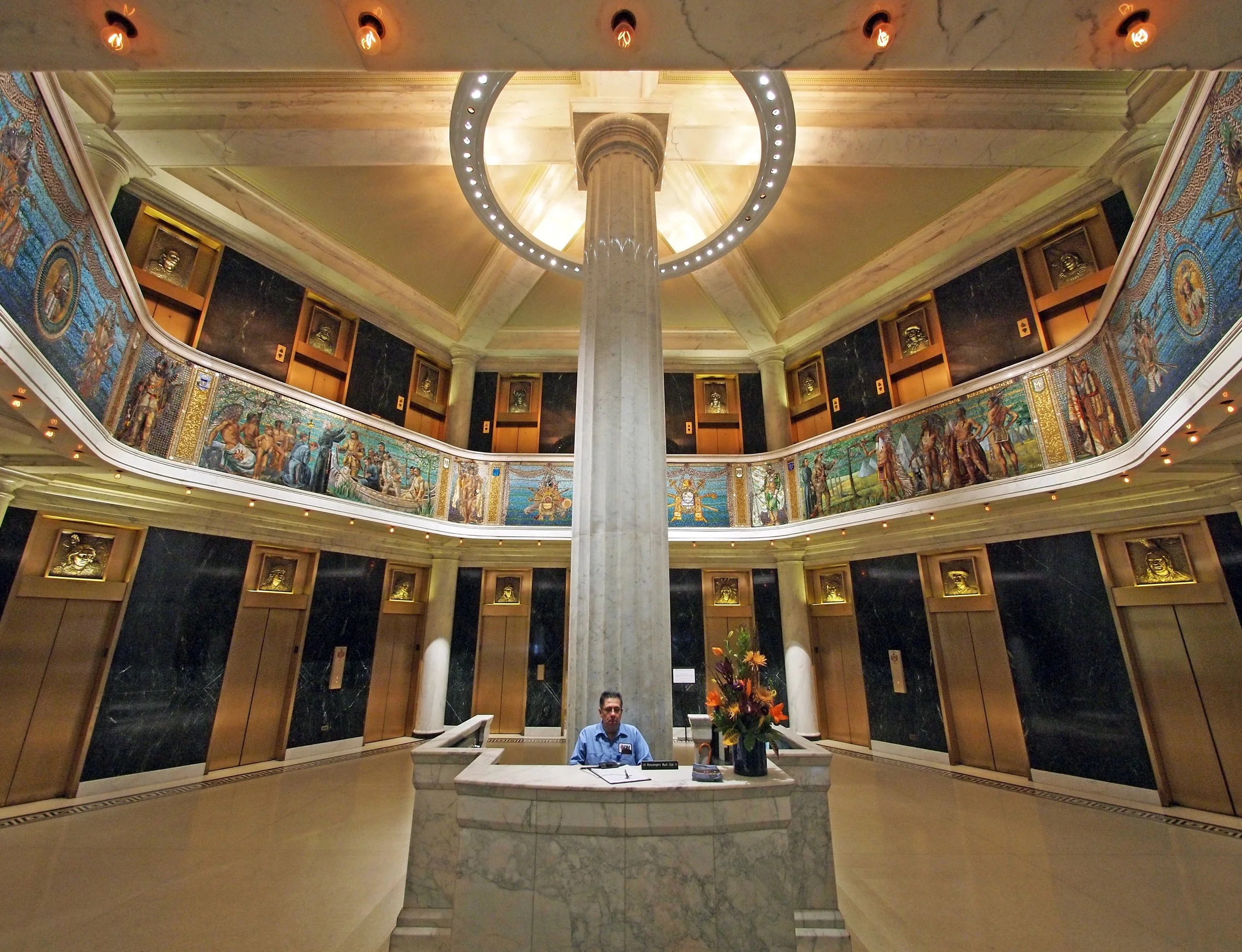 A security guard sits at a desk under mosaics celebrating the indigenous people of the United States. Drives & Detours Chicago Loop walking tour