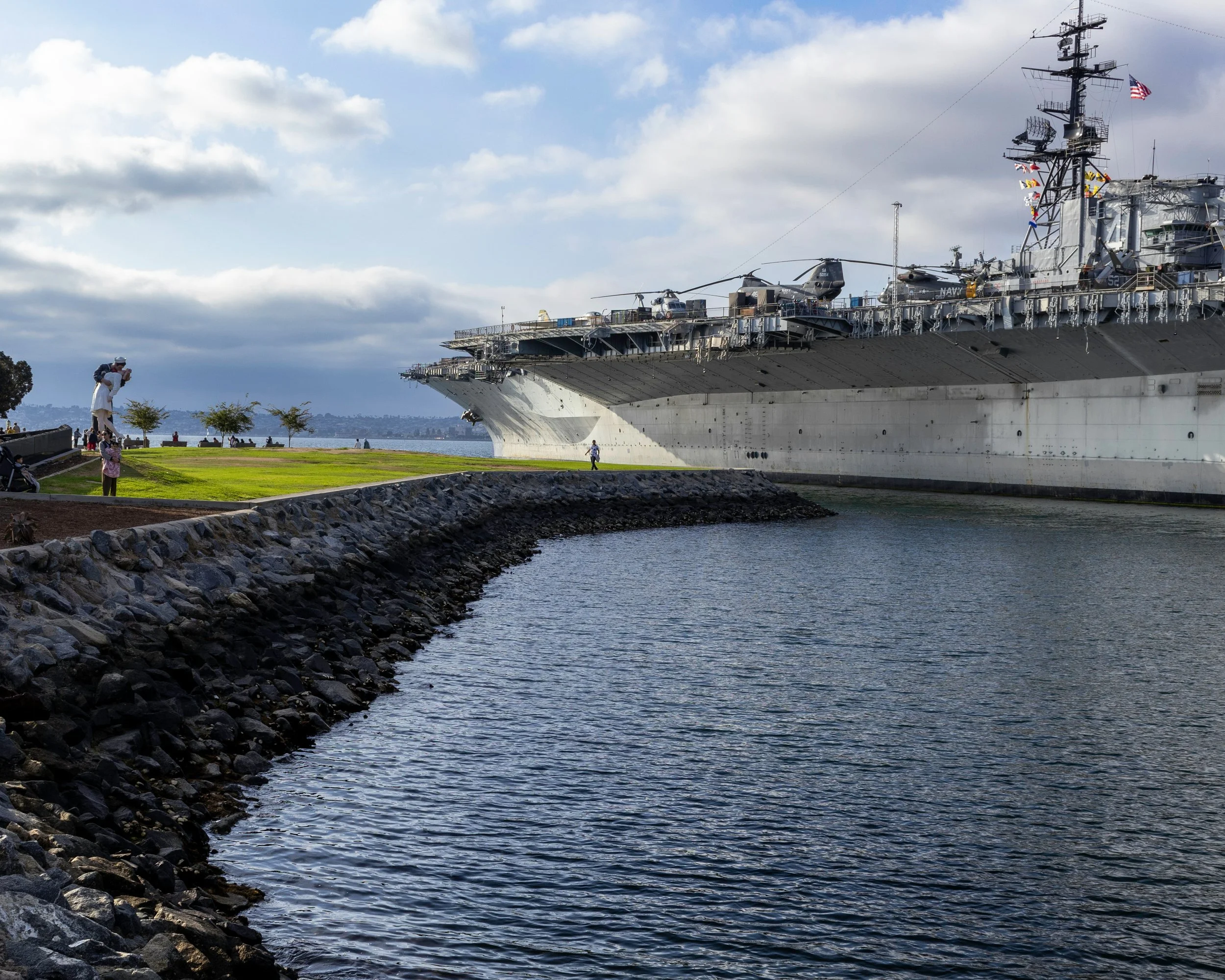 The USS Midway Museum towers over a small park holding a sculpture called Unconditional Surrender. This shows a sailor kiising a woman in Times Square, New York, and is based on the iconic photograph