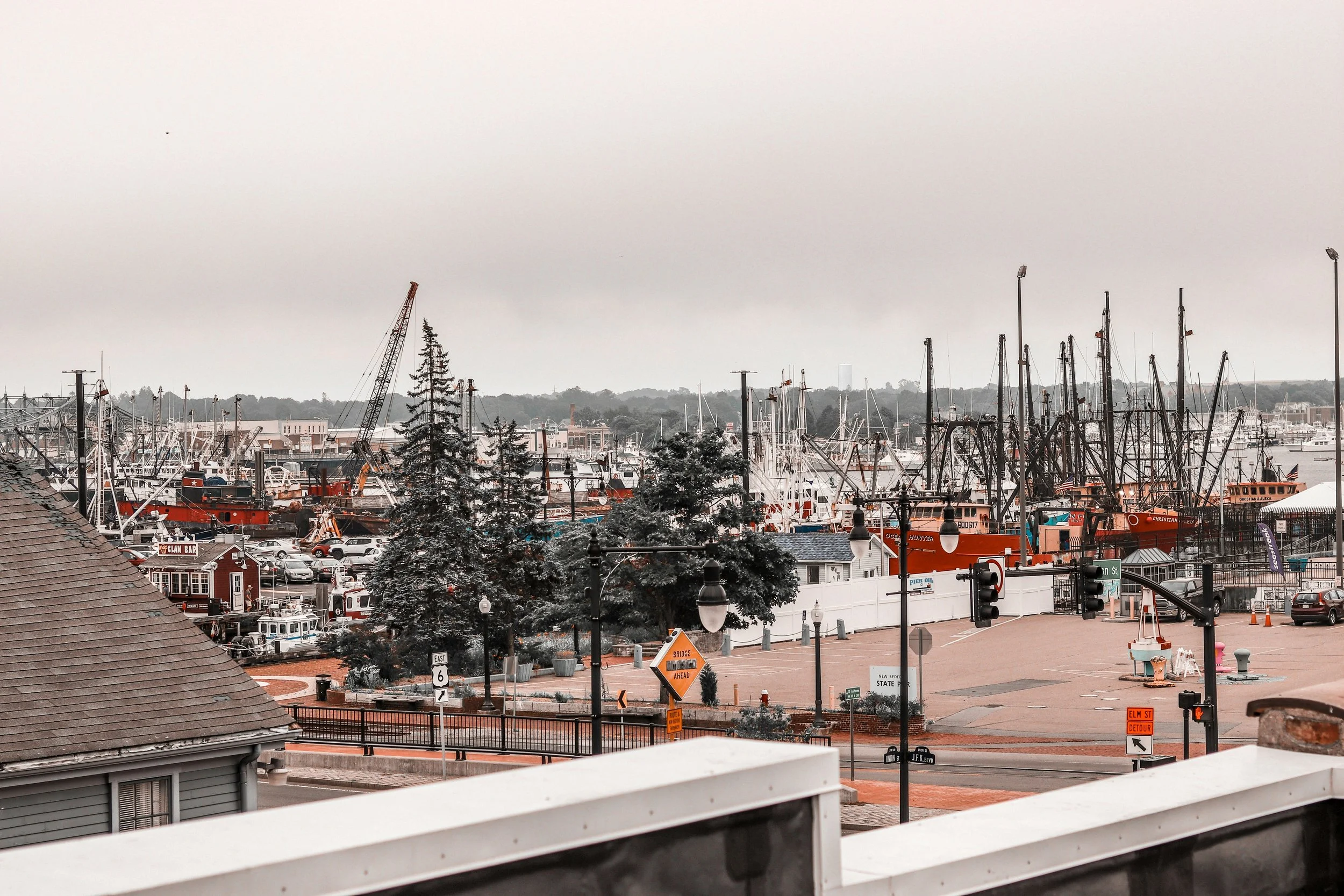 A harbor is full of ships at port under grey skies in Masssachusetts. Drives & Detours New Bedford walking tour