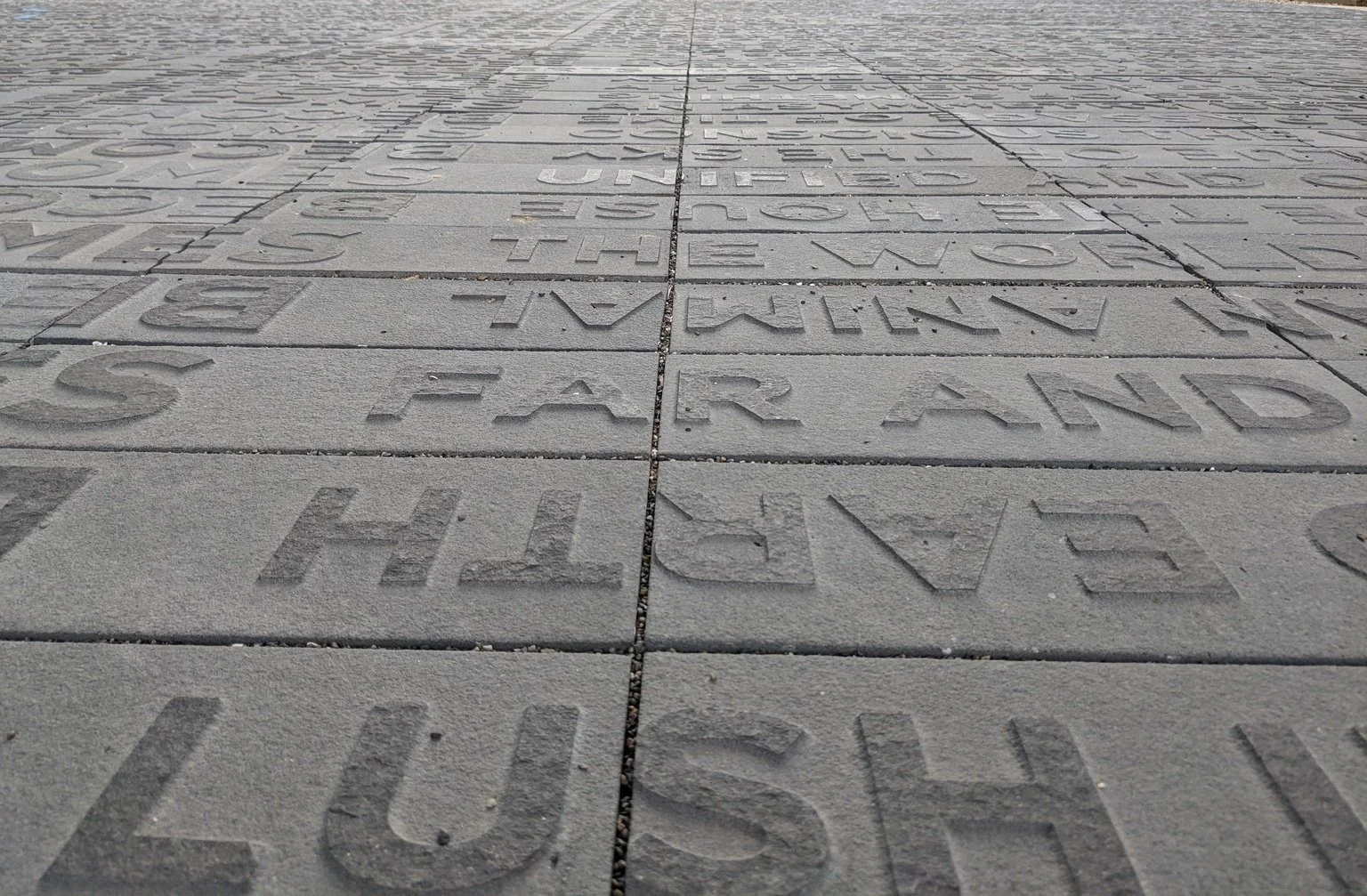 KAHNOP • TO TELL A STORY by Ann Hamilton at UCSD. It shows rows and columns of words embossed on stone, almost like they're printed on the ground