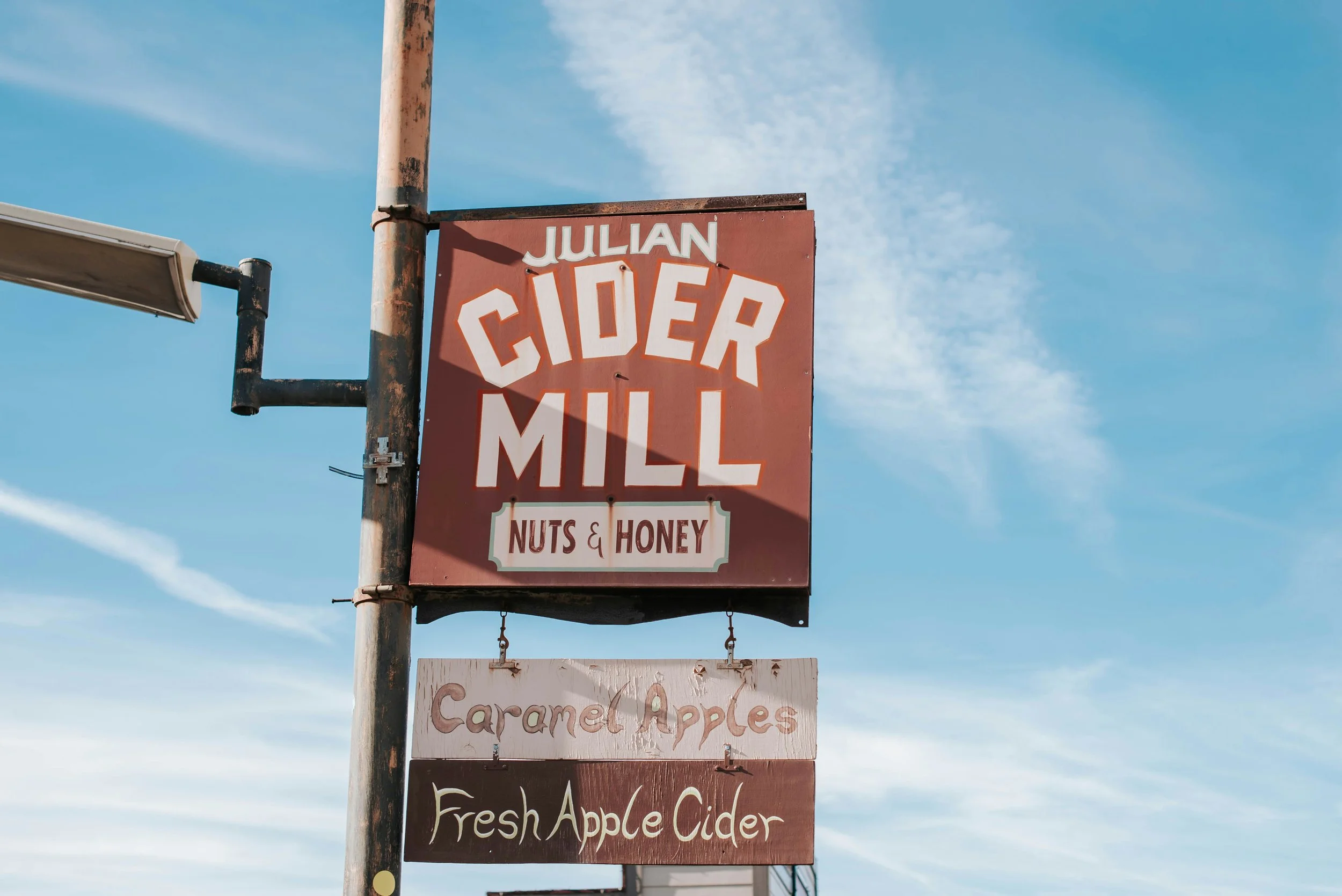 Old, weathered signs in Julian, California. They read: Julian cider Mill, Nuts & Honey, Caramel Apples, Fresh Apple Cider