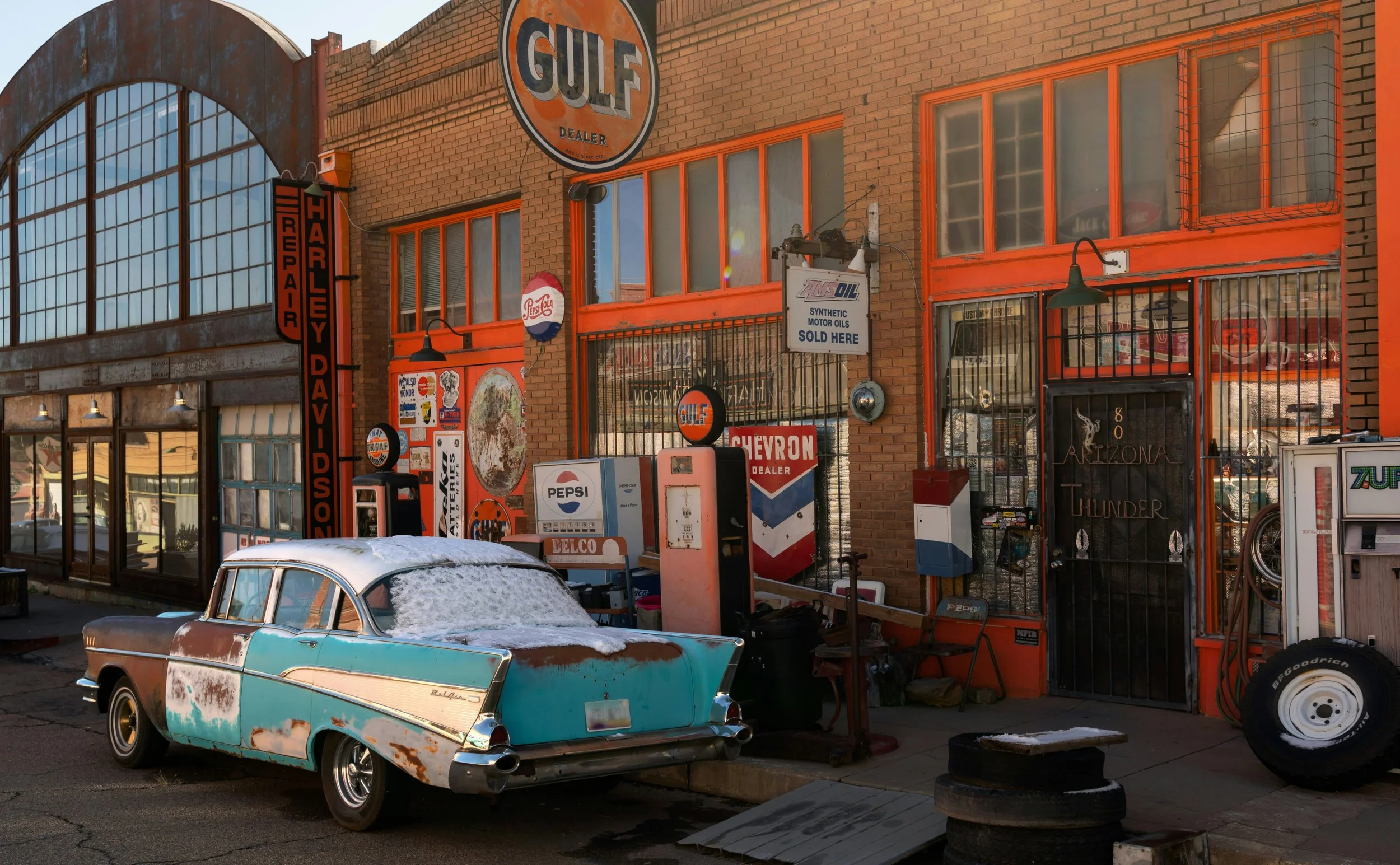 An old, rusted American muscle car sits outside a classic Gulf gas station in Lowell, Arizona. Drives & Detours Bisbee Tour