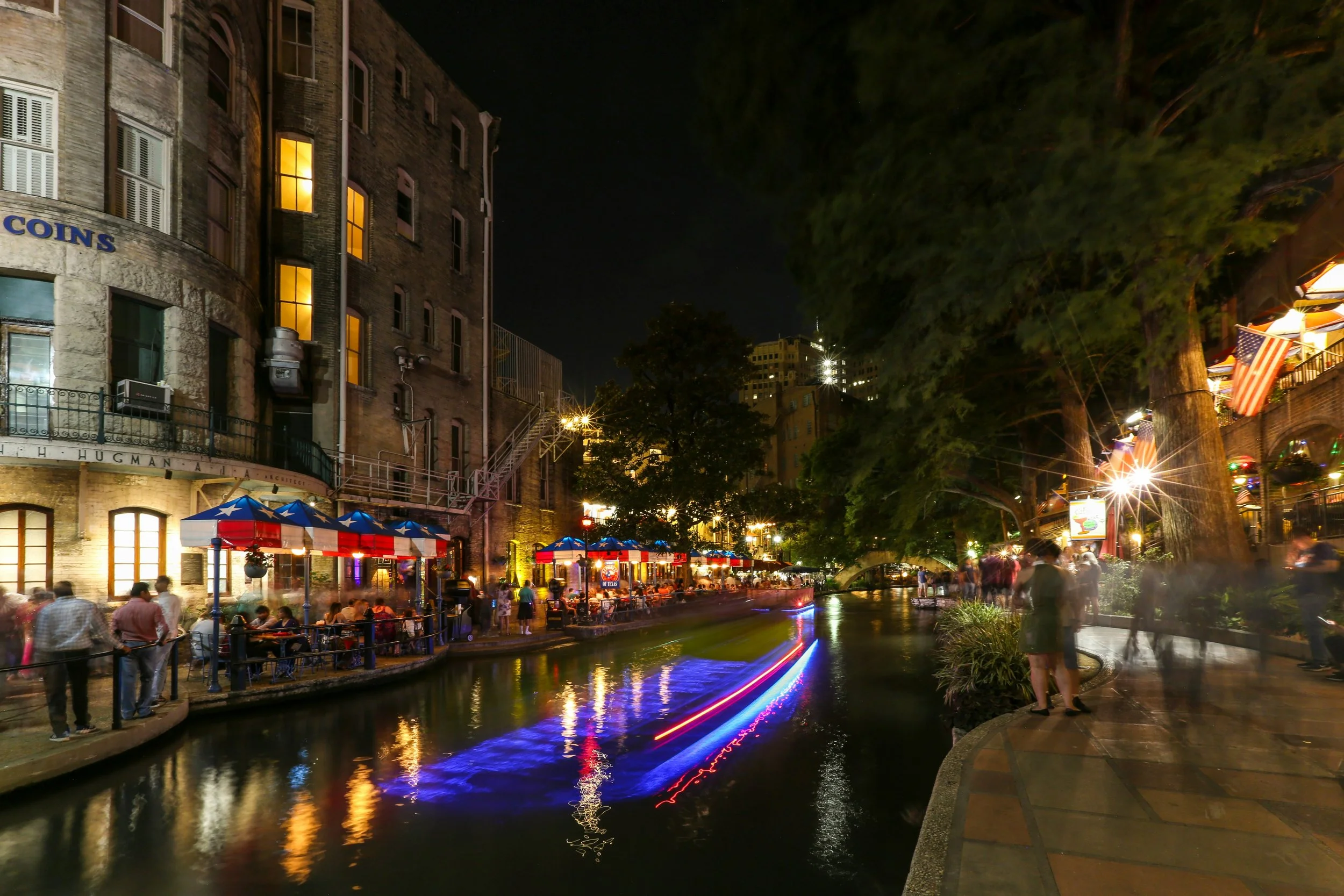 People walk and eat in restaurants beside the San Antonio River. Robert Hugman’s office can be seen in the corner.