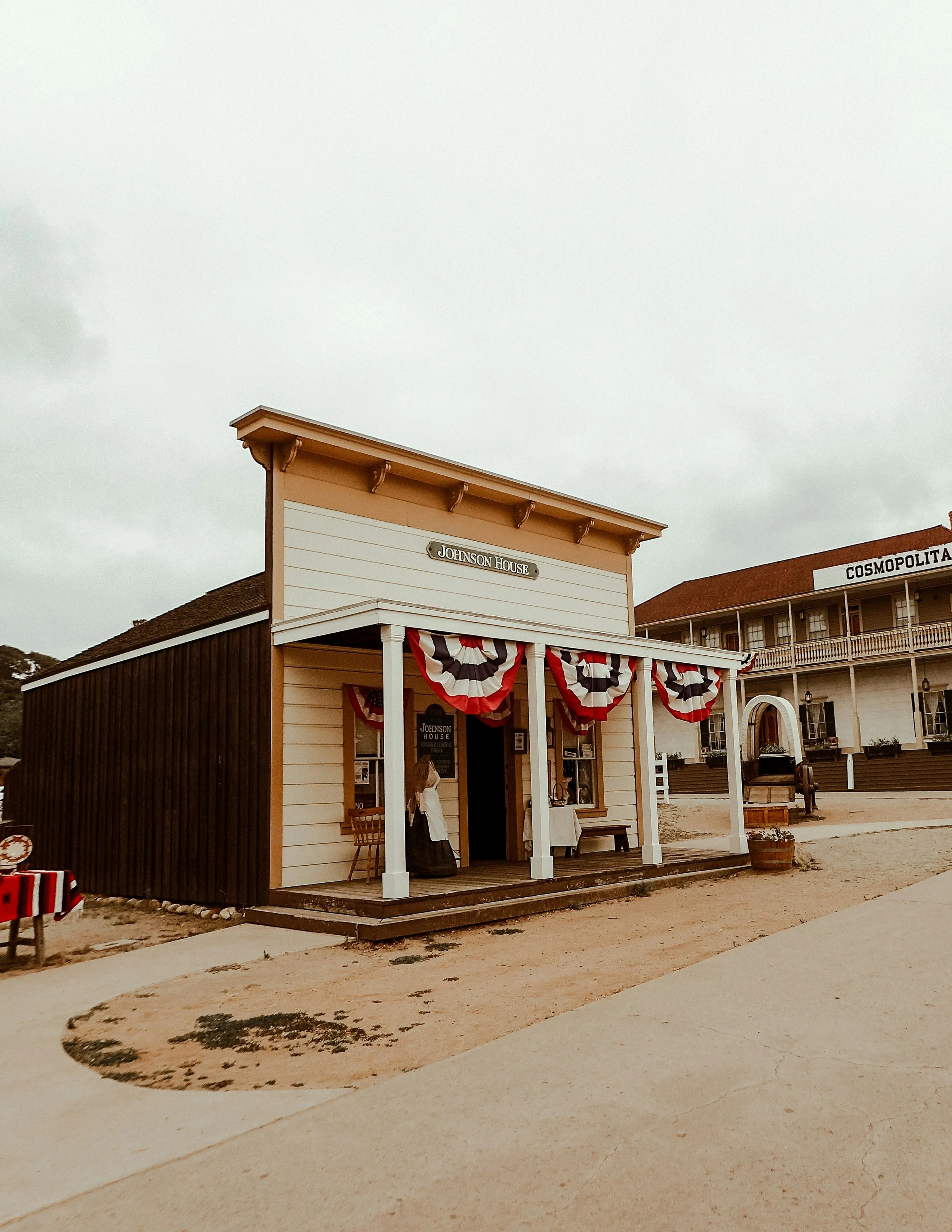An old wooden building named Johnson House in Old Town San Diego State Historic Park. It is one storey, and flies red, white and blue bunting