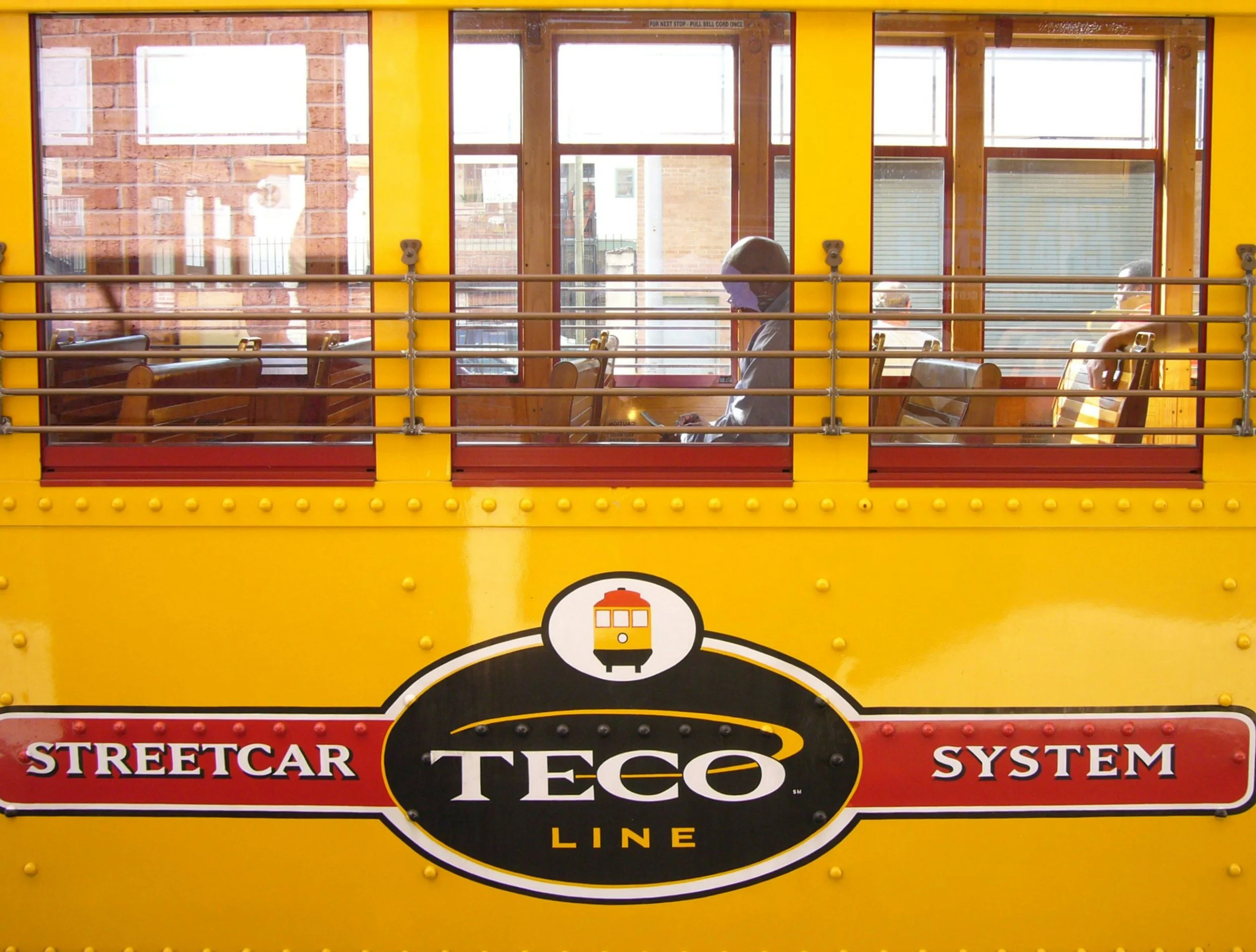A man sits on a yellow TECO streetcar in Tampa. Drives & Detours Tampa local tips