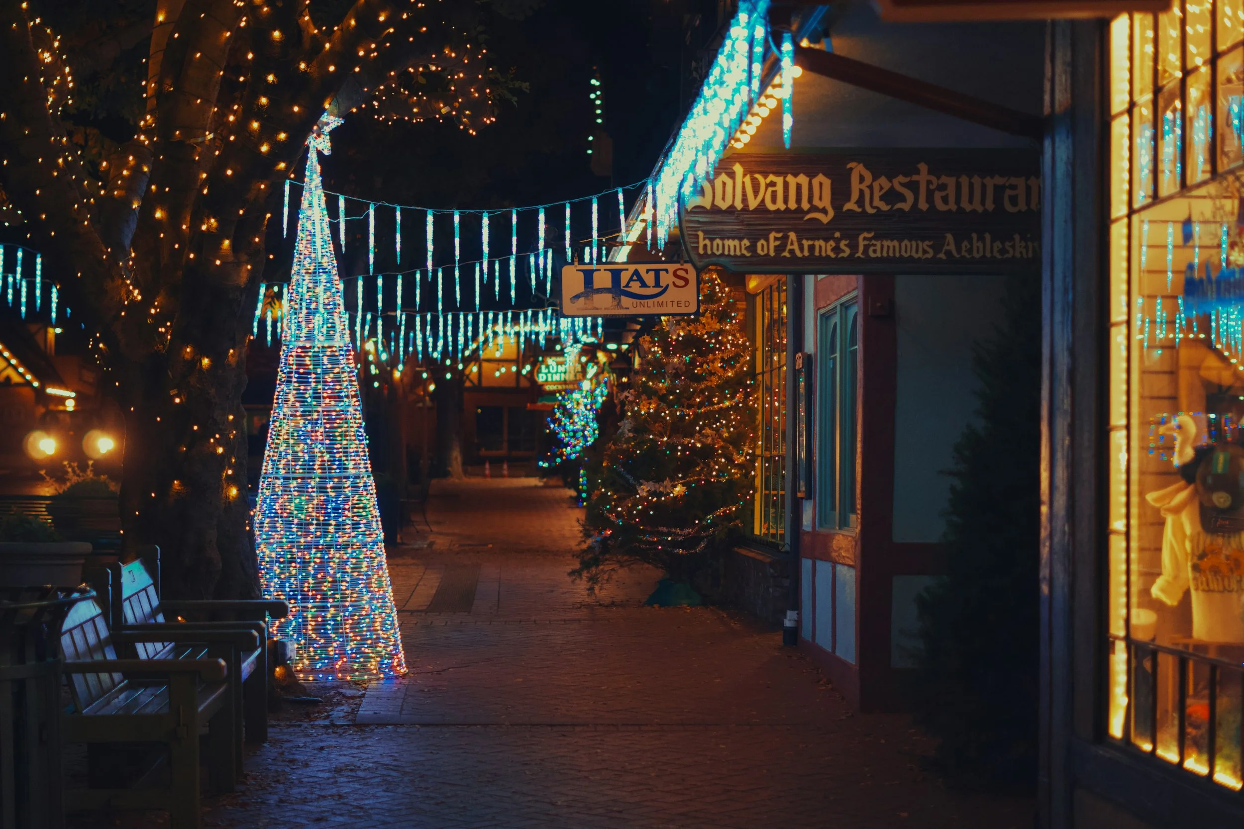 fairy lights and a christmas tree can be seen on a street in downtown Solvang.