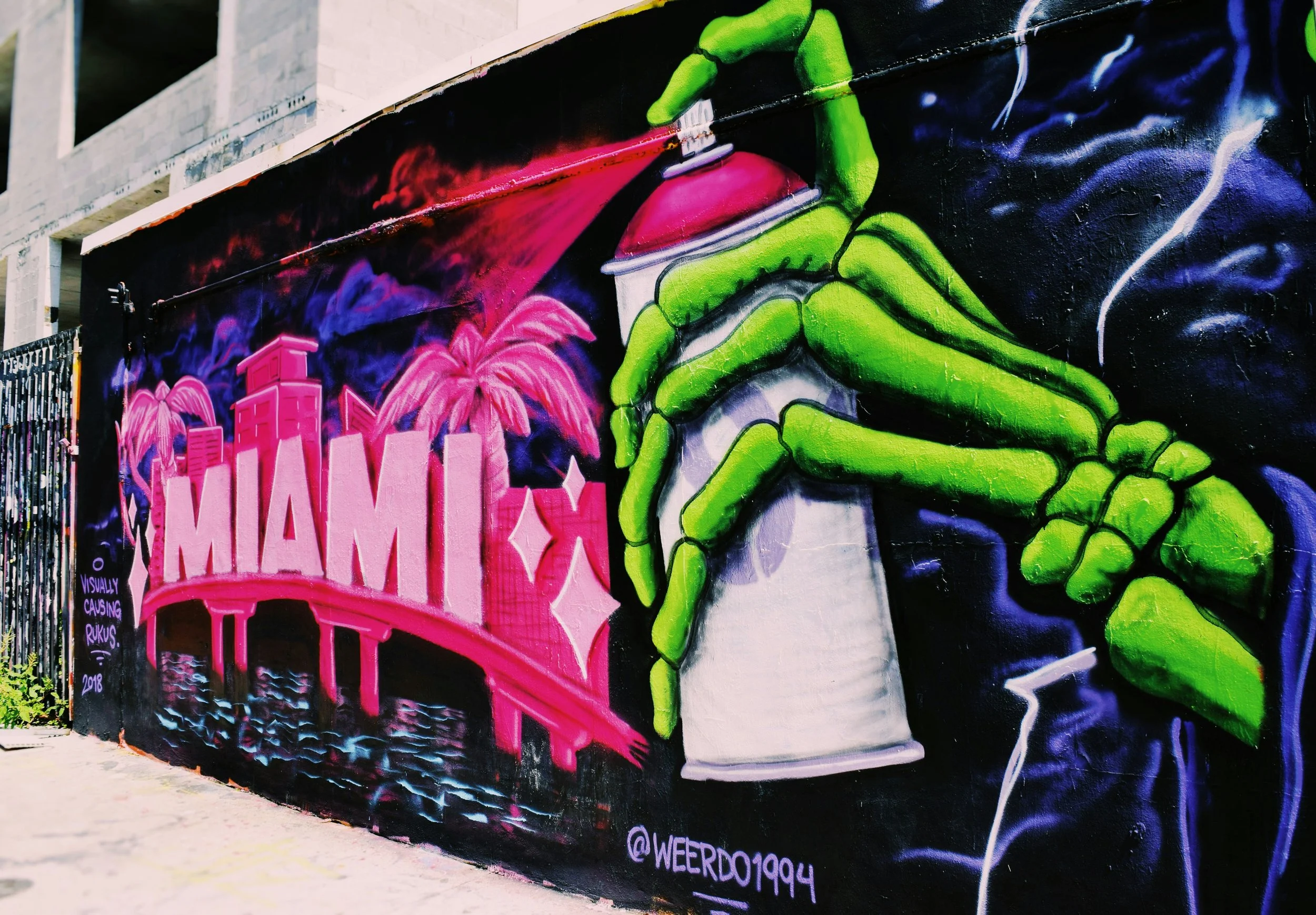 The hand of green skeleton spraypaints the word: Miami, with tower blocks and palm trees onto a wall. best places to eat in Wynwood
