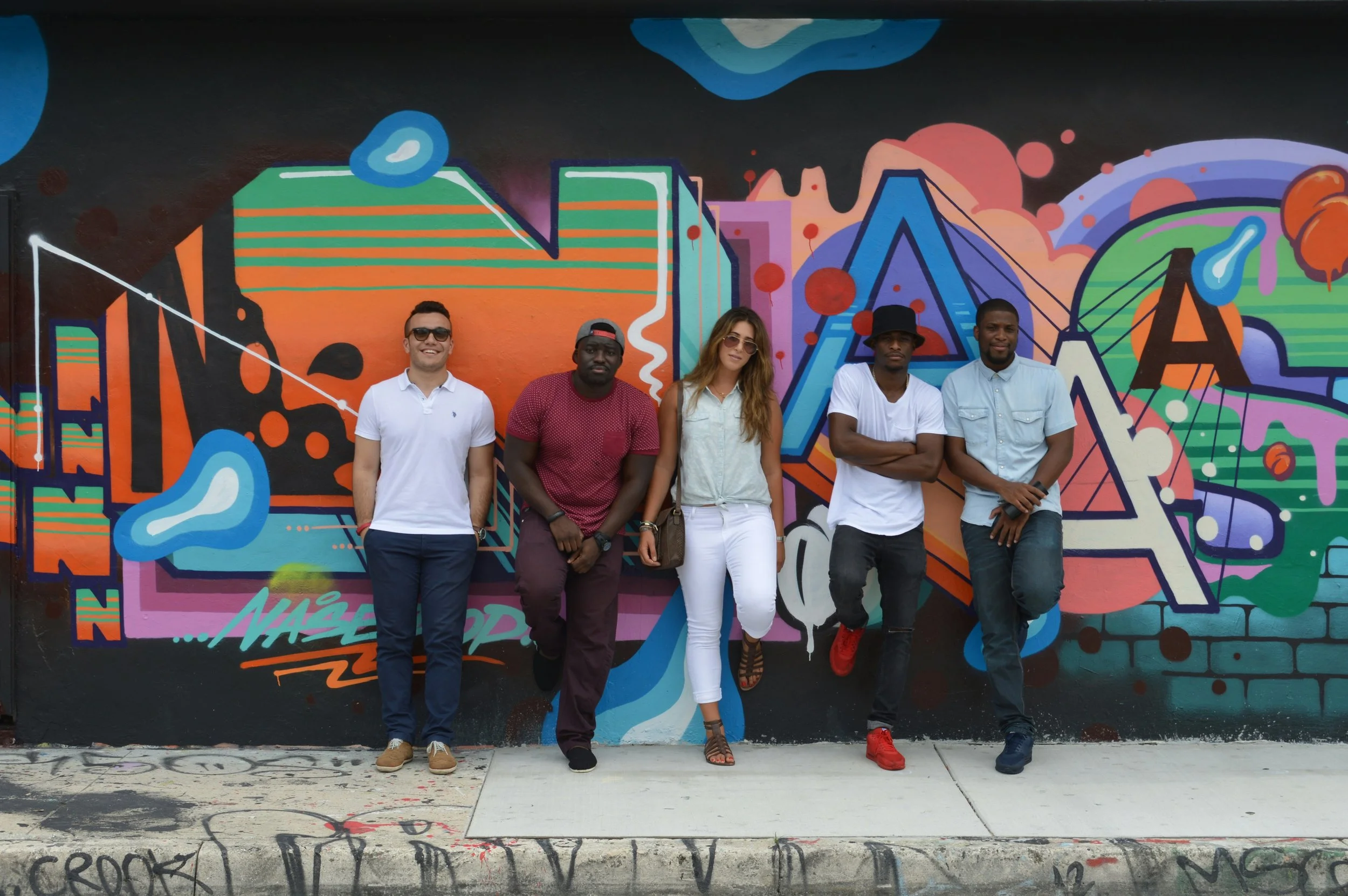 A group of people stand against some street art in Wynwood, Miami.