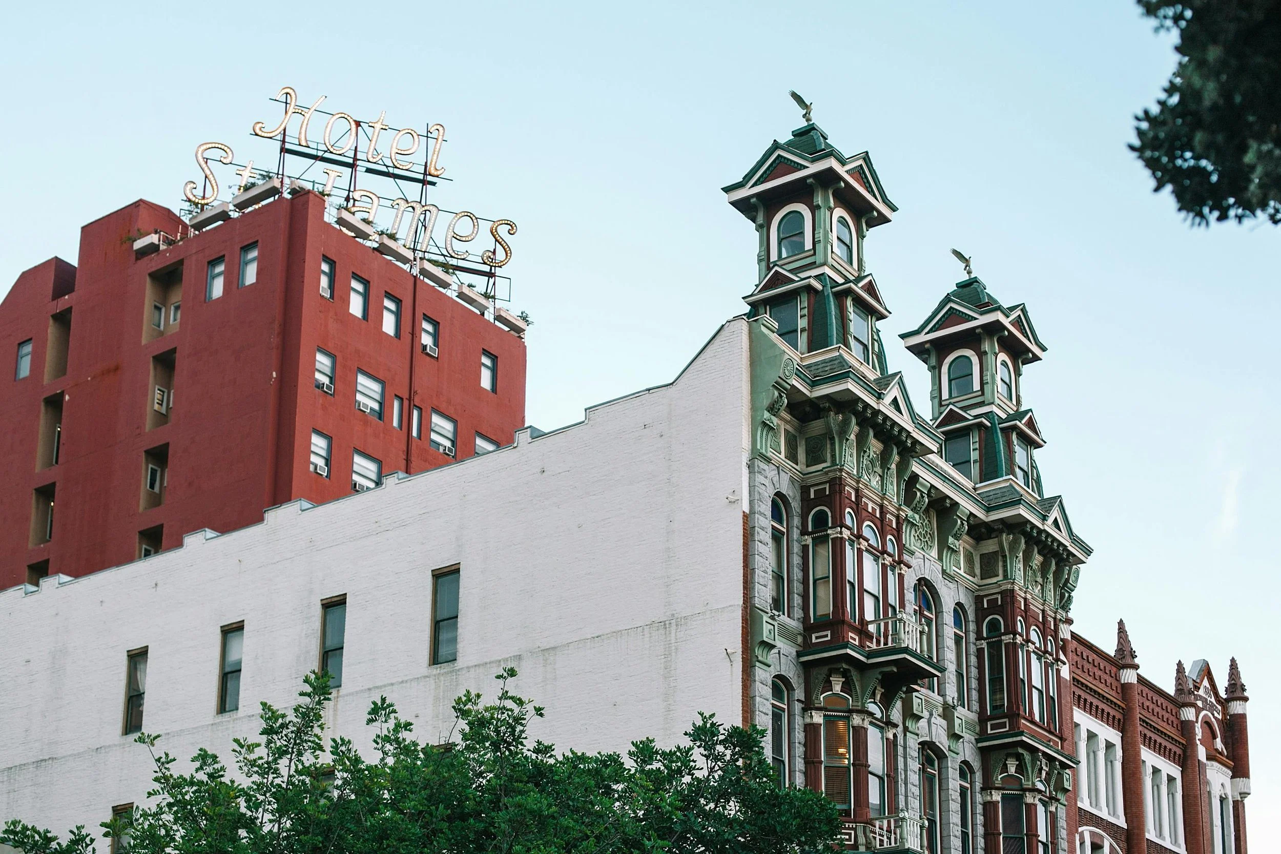 An old building, painted green and with two turrets, stands in front of the St James Hotel in the Gaslamp Quarter, San Diego