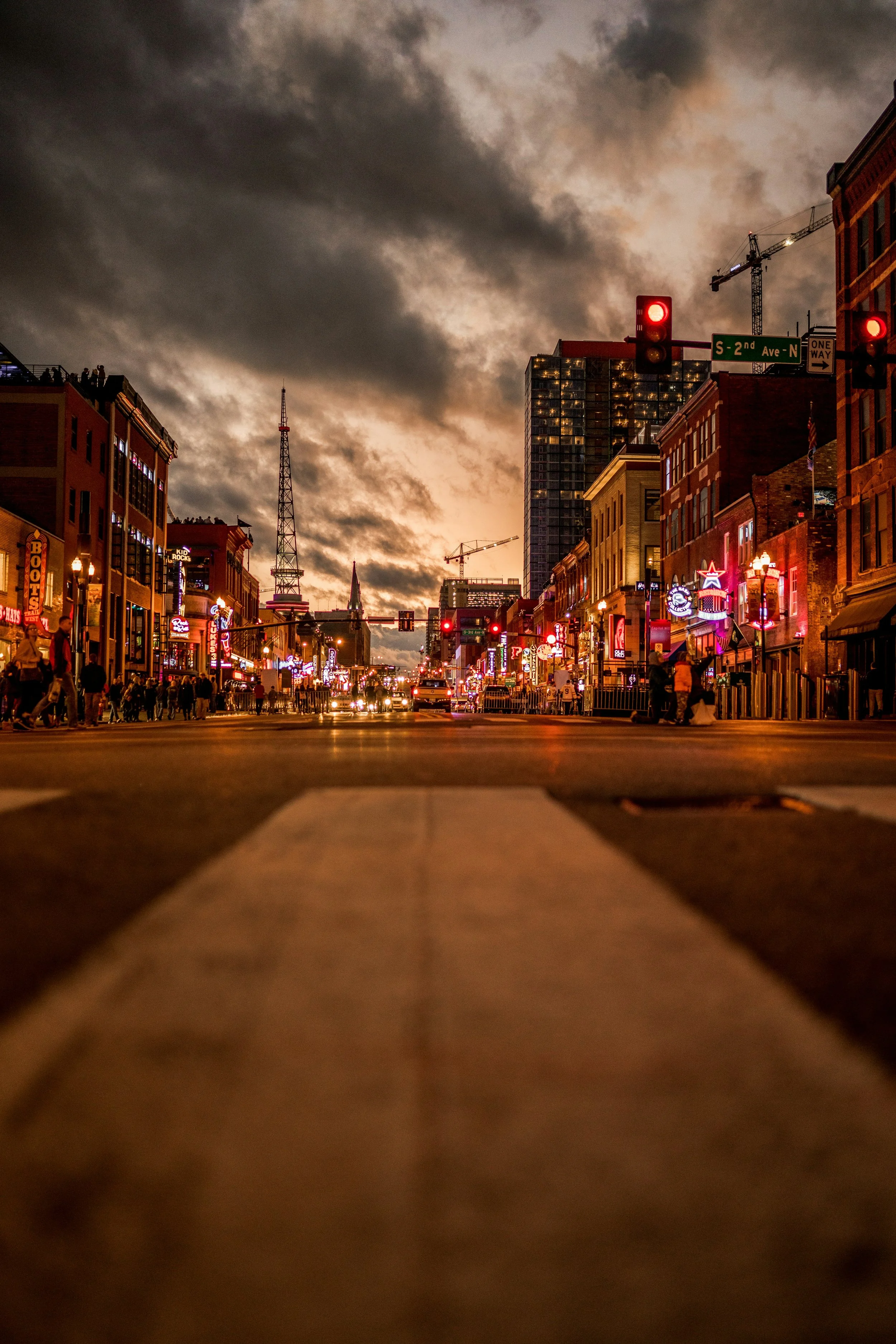 Broadway in Nashville, Tennessee, at dusk. It's a very low shot from the center of the busy road showing lights everywhere. Drives & Detours Nashville self-guided tour