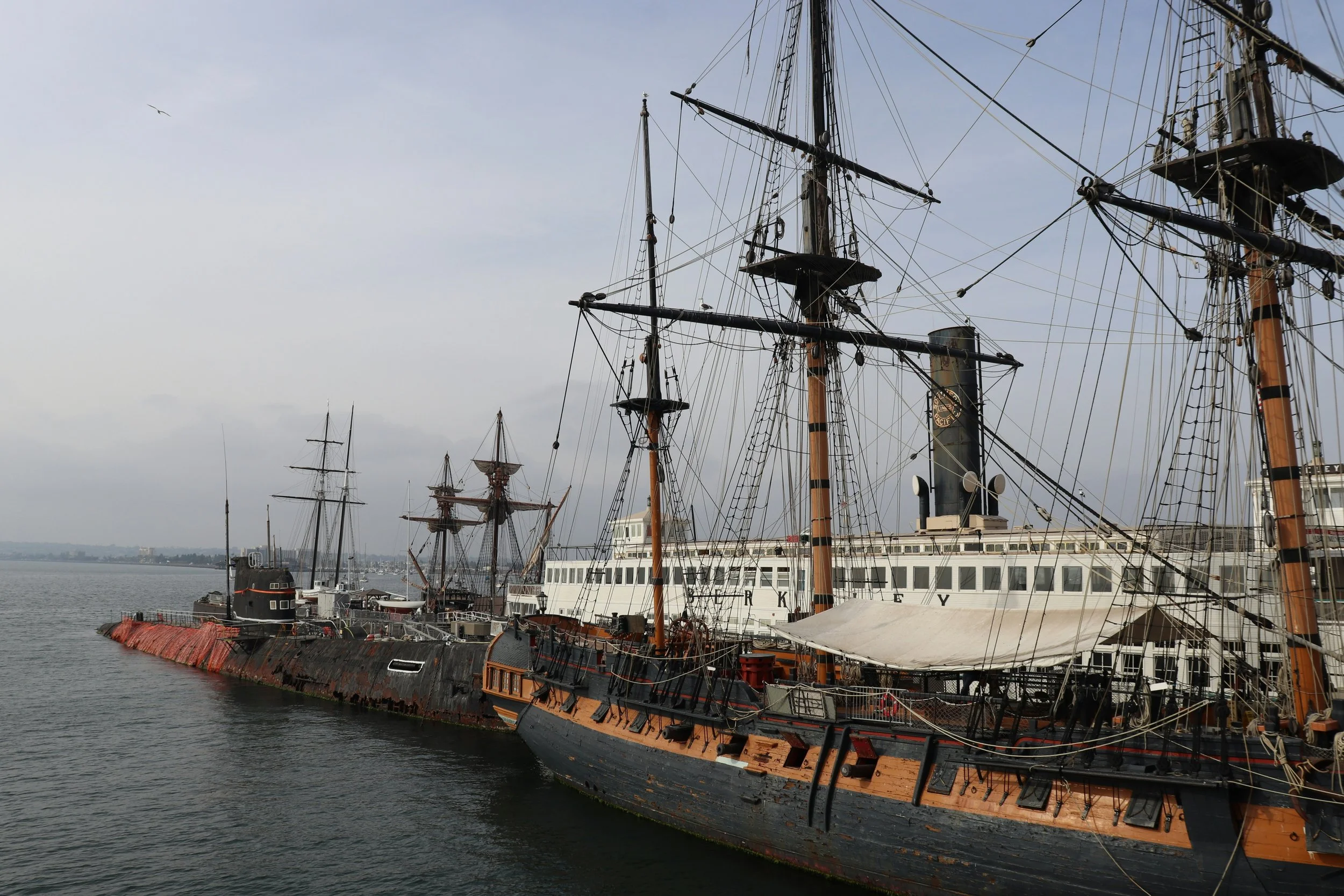An old, wooden tall ship floats in front of a submarine at the Maritime Museum. Drives & Detours Things to Do at the San Diego Embarcadero