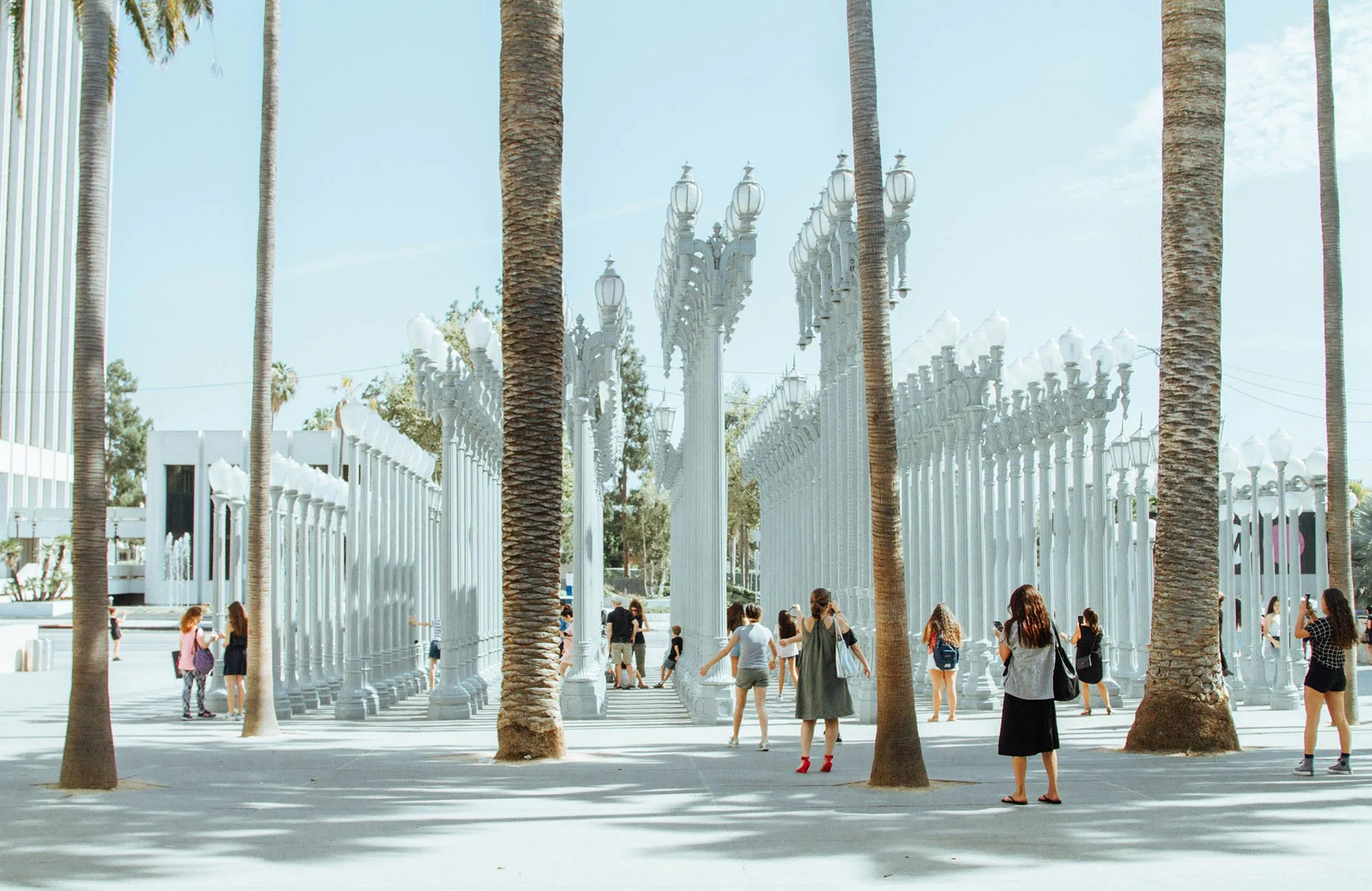 People walk through an art installation of white vintage street lights in Los Angeles. Drives & Detours Solo travel city guide