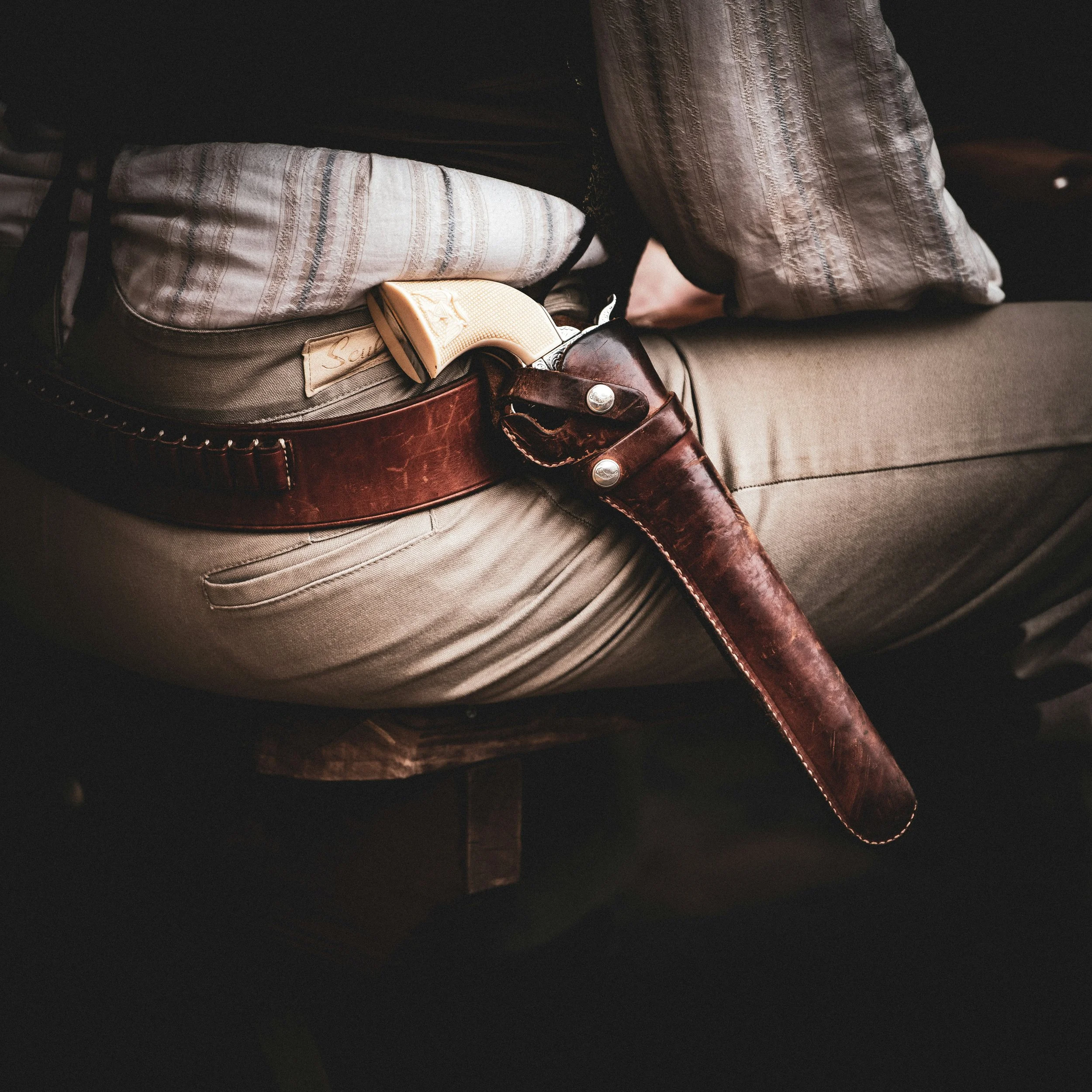 A close up of an old six shooter pistol in a holster on a man’s hip. Drives & Detours Deadwood tour