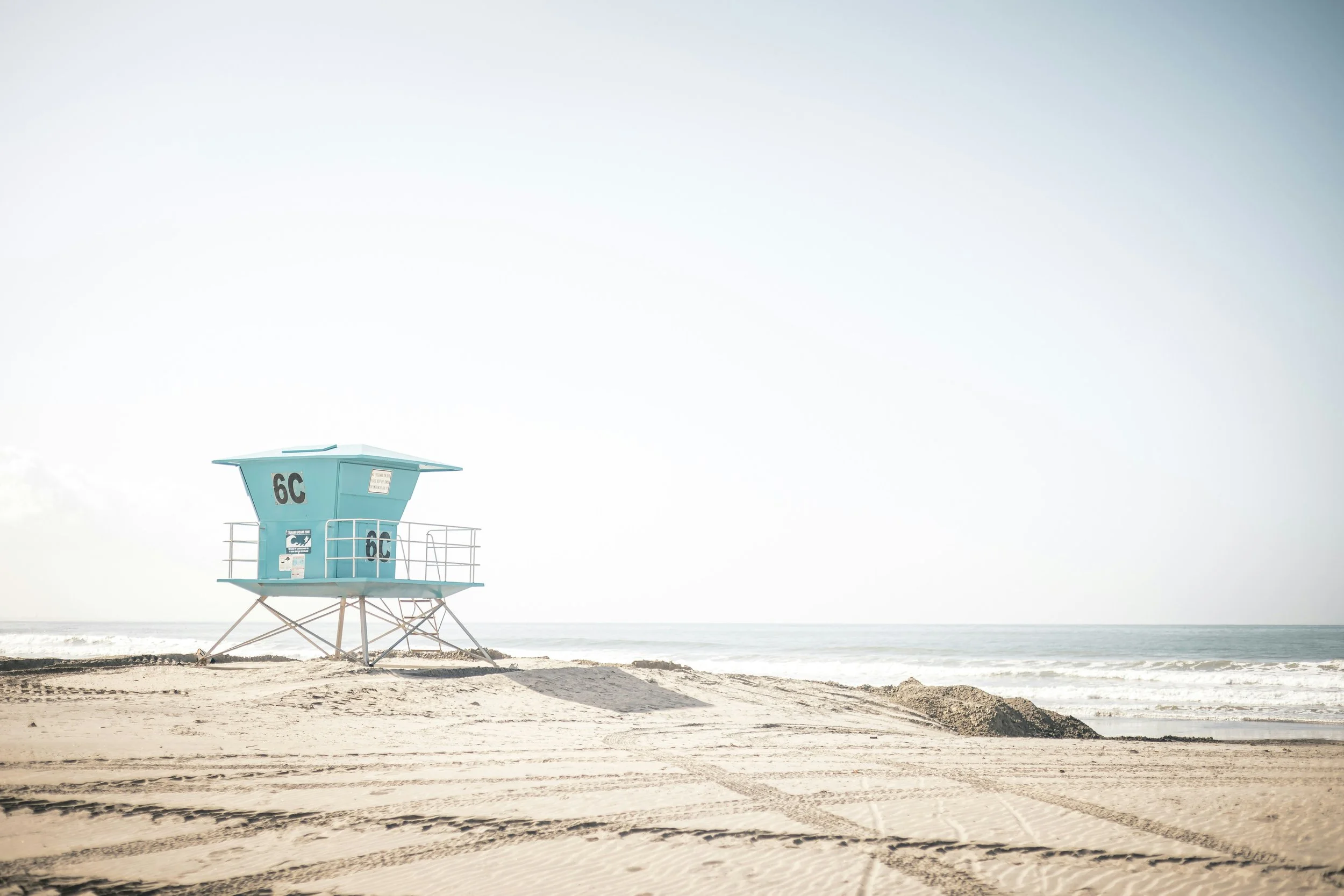 A pastel blue lifeguard hut on Coronado Beach. The whole picture is very soft. The sky, sea and sand almost blend into each other with only the hut standing out