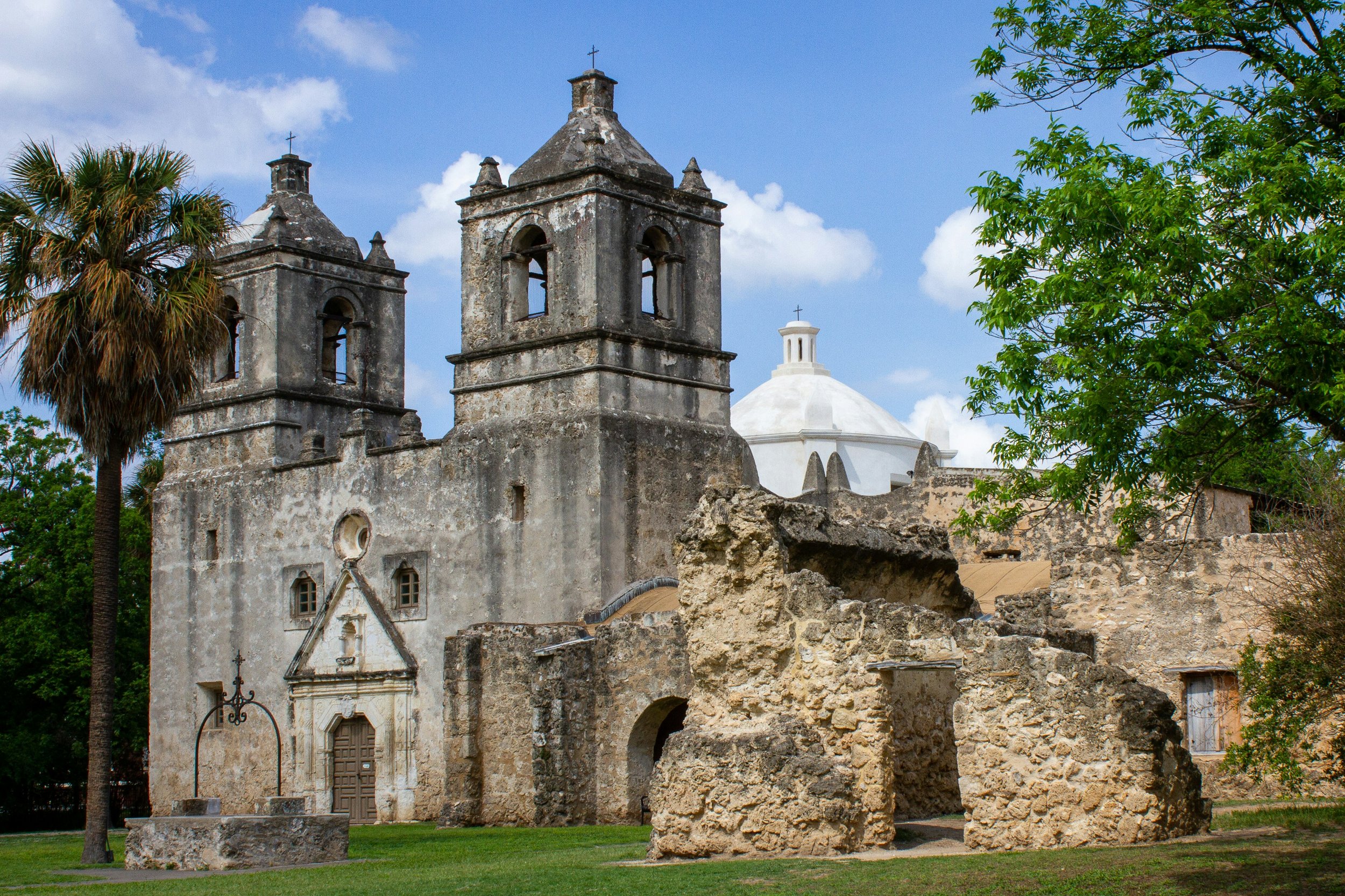 Mission Concepción, one of the San Antonio Spanish Missions, is well preserved. The large Spanish colonial church has a palm tree in front of it and some ruins to its right