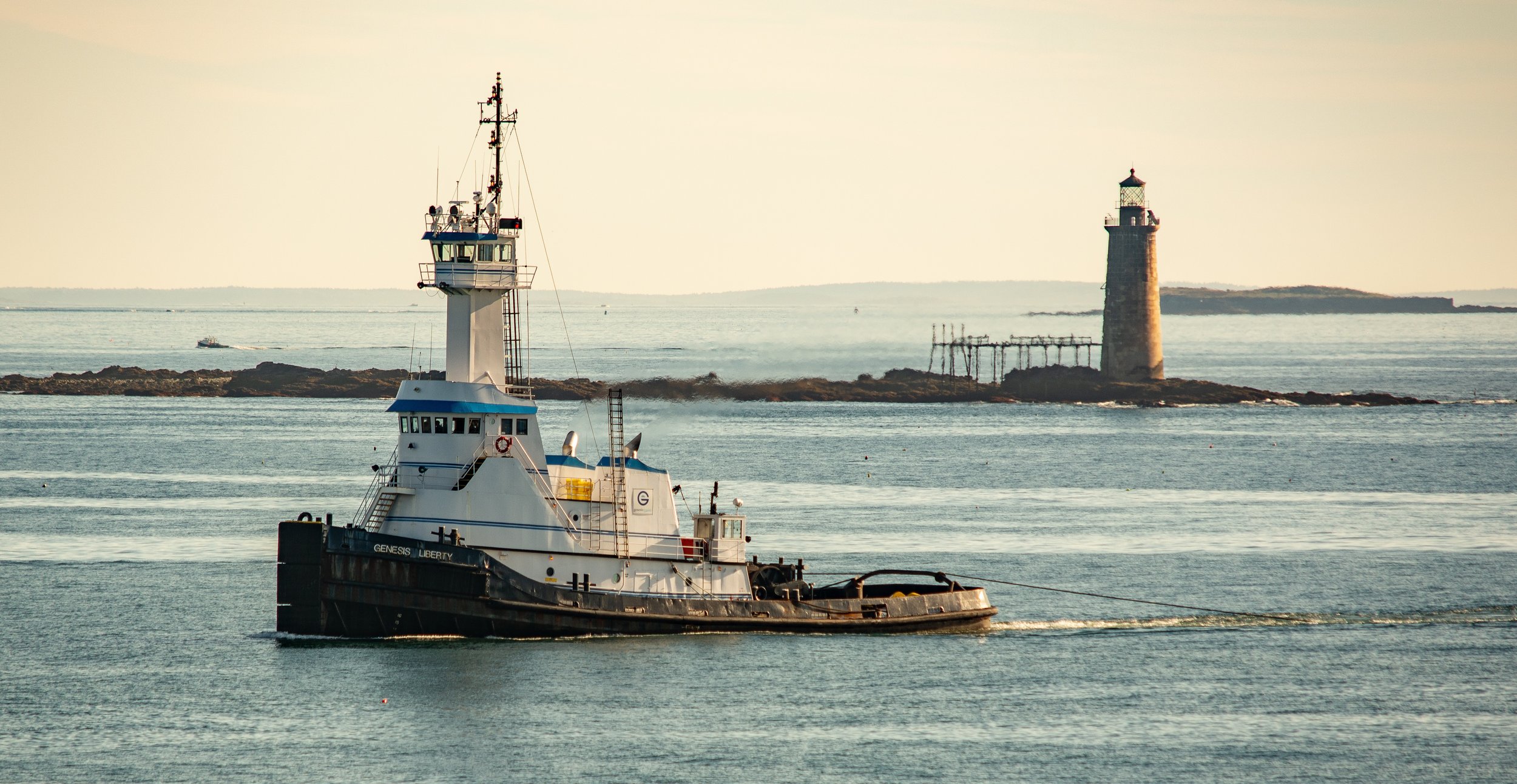A tug boat sails through the still waters of the New England coast at Portland, Maine