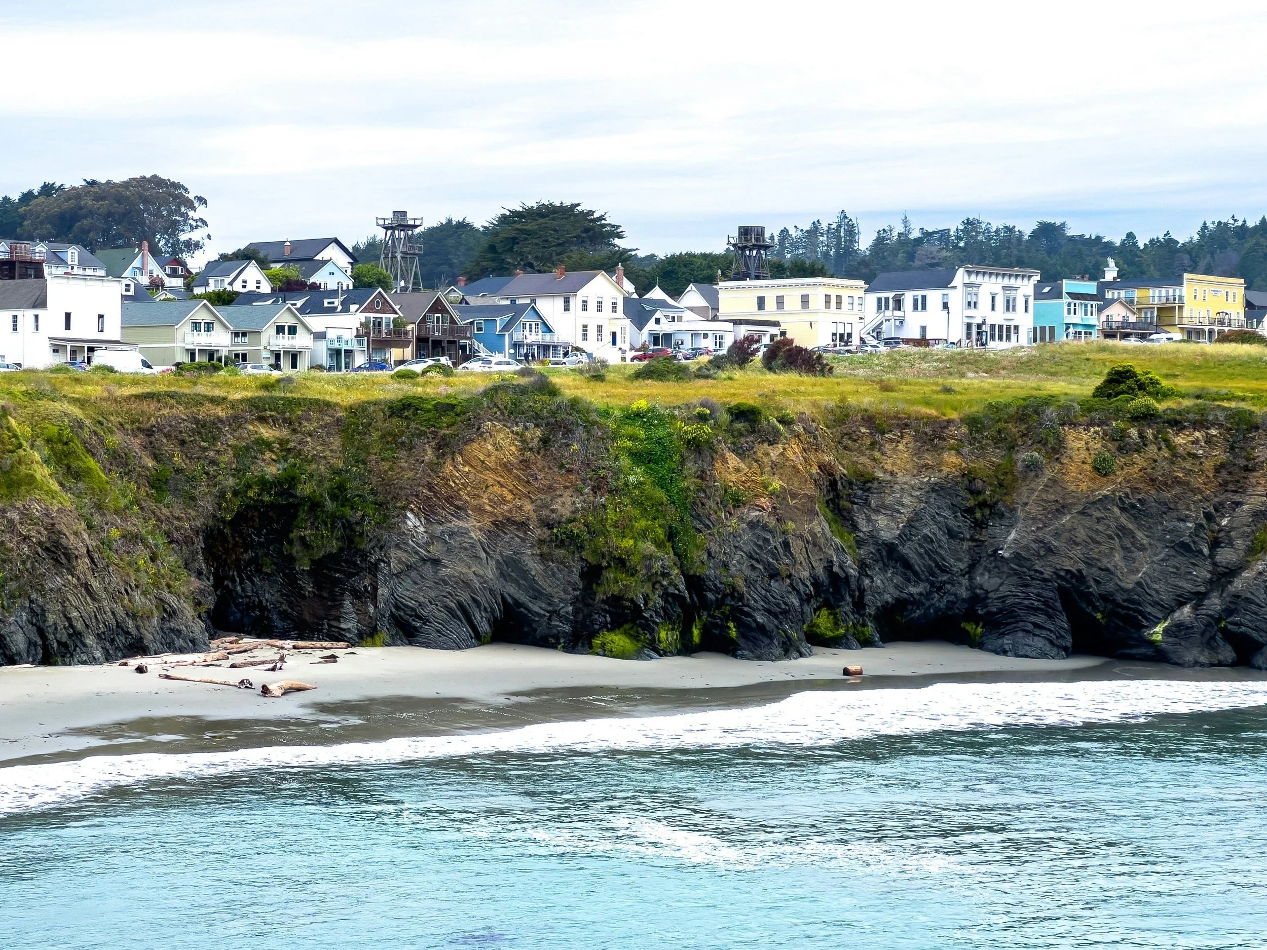 Old houses are built along the top of a cliff, like something from Murder She Wrote. Drives & Detours Mendocino walking tour