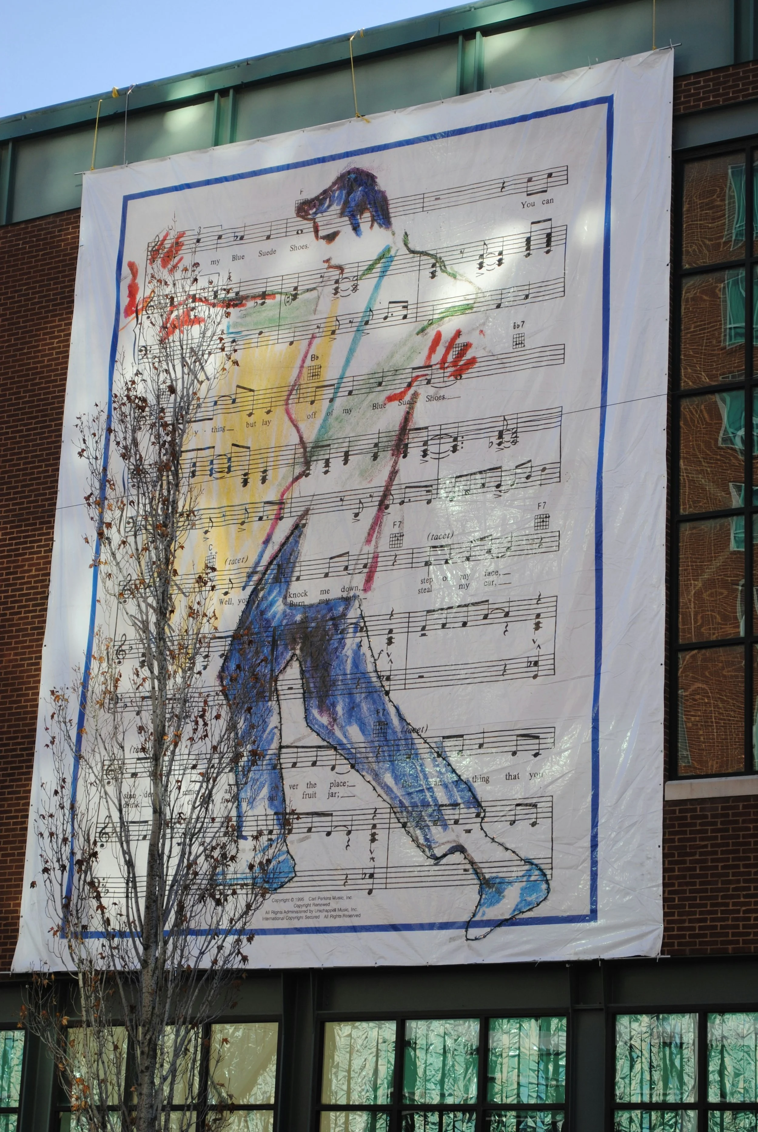 A piece of street art that shows a mulitcolored Elvis drawn over a piece of sheet music for Blur Suede Shoes. Drives & Detours Memphis walking tour