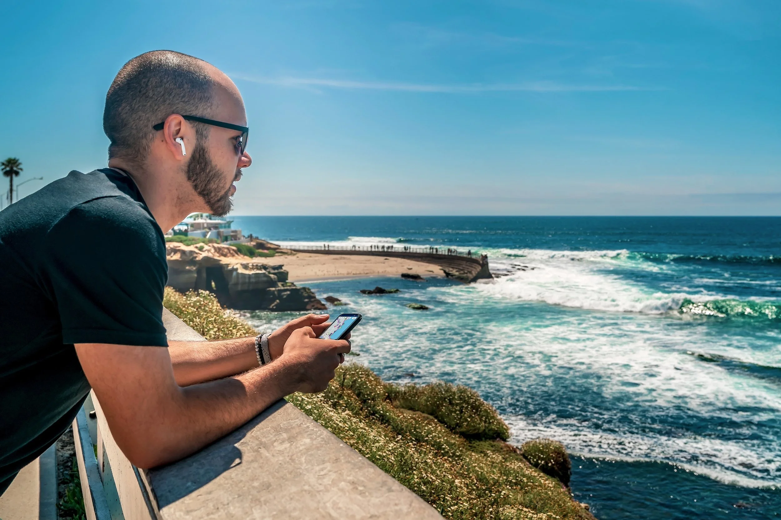 A man looks over the ocean listening to a Drives & Detours self-guided tour