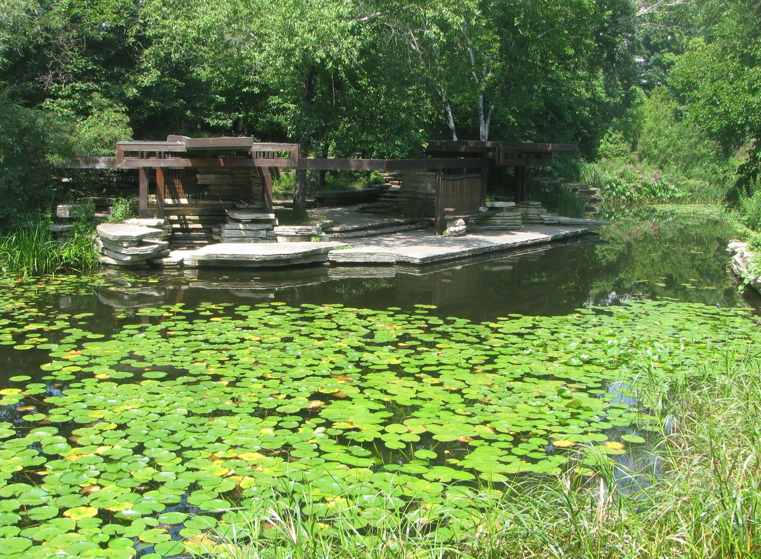 Wooden pagodas sit on a stone island surrounded by water flowers in the Alfred Caldwell Lily Pool. Drives & Detours Chicago hidden gems