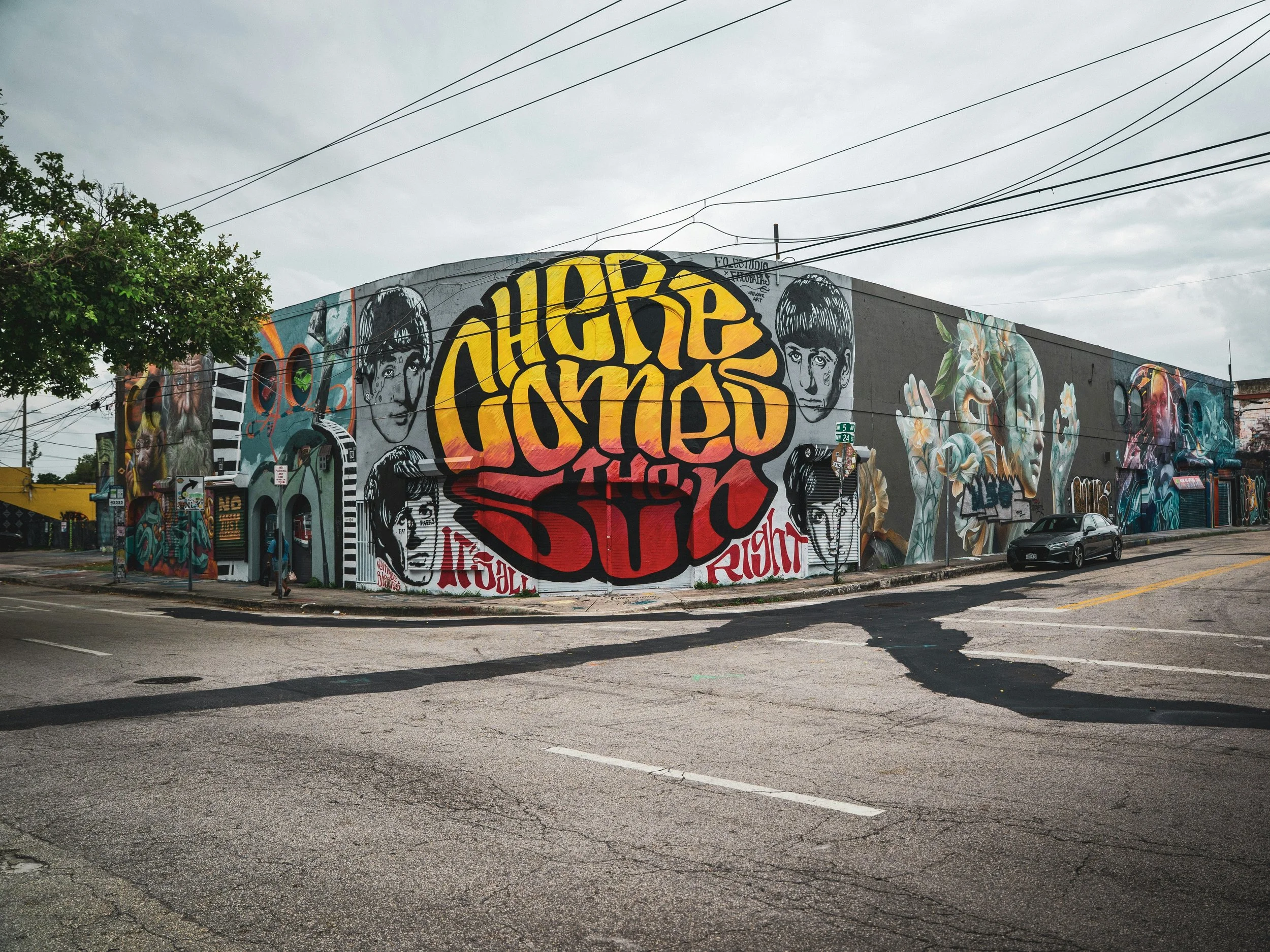 The faces of the Beatles and the lyrics: Here comes the Sun, are painted on a street corner in Miami. Drives & Detours Wynwood art walking tour