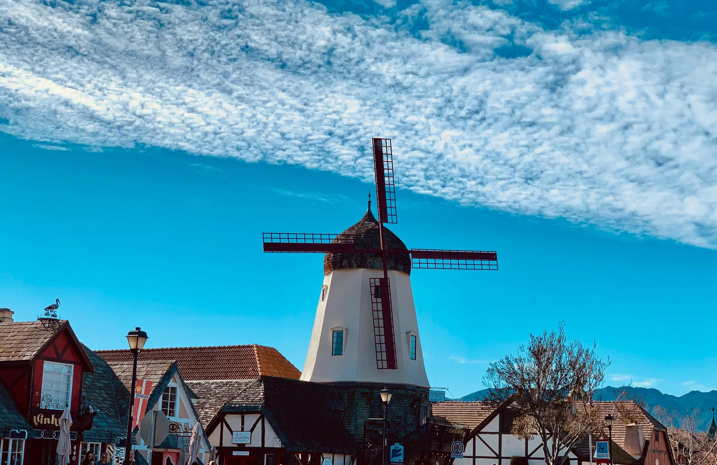 A white windmill with black sails and a bright blue sky in California. Drives & Detours Top sights in Solvang California