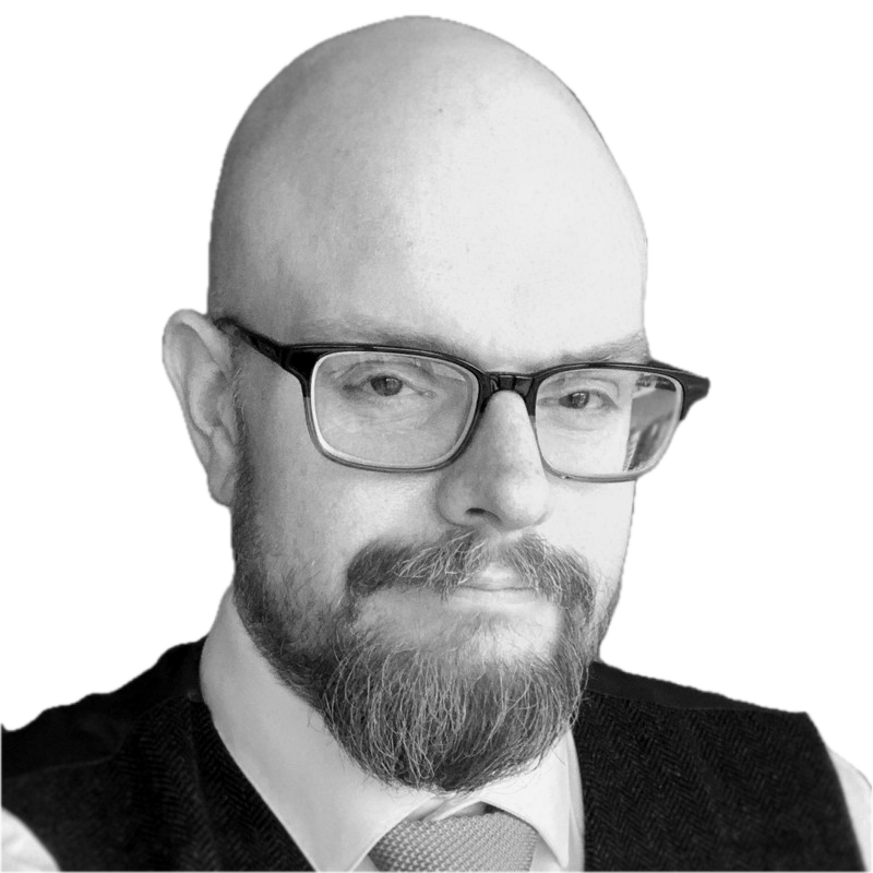 Ian Hoch, a grayscale photo of a man with glasses, a beard, and a mustache, wearing a suit and tie.