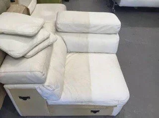 Section of a white couch with a pull-out bed, flanked by folded cushions.