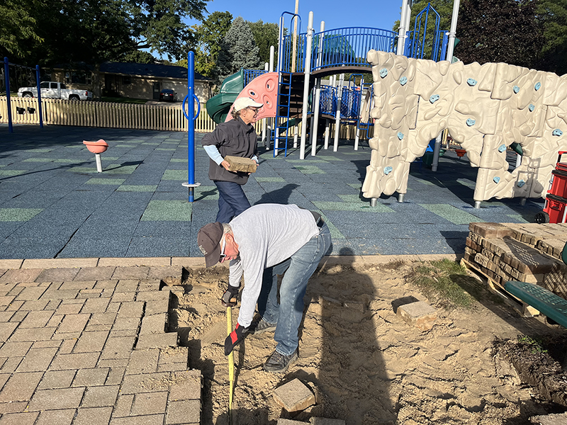 Volunteers move pavers in Sonshine Community Park to prepare the school expansion construction site
