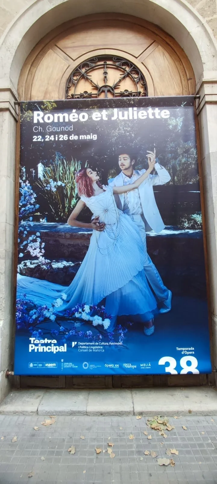 The poster advertises a theatrical production of Romeo and Juliet, showing a man and woman dancing in elegant costumes, with event details written in Spanish.