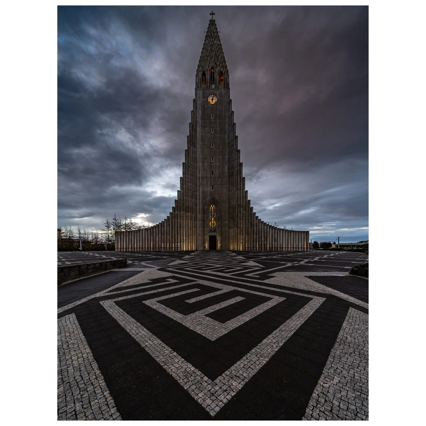 The towering Hallgr&iacute;mskirkja stands as Reykjavik&rsquo;s poetic beacon, its minimalist design inspired by the basalt columns of Iceland&rsquo;s volcanic terrain. Under a moody twilight, the church&rsquo;s glow warmly contrasts the stormy sky, 