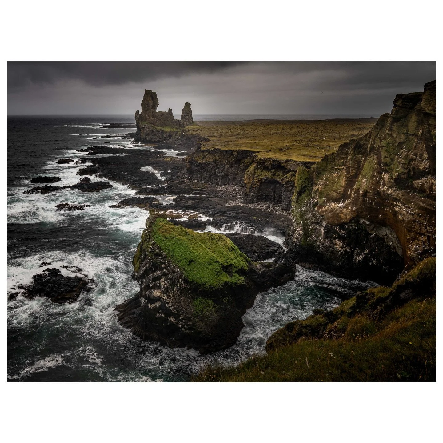 The Atlantic crashes against Iceland&rsquo;s forgotten guardians. These volcanic remnants at L&oacute;ndrangar tell stories older than memory, standing defiant as white foam swirls around their basalt foundations and emerald moss clings to every weat