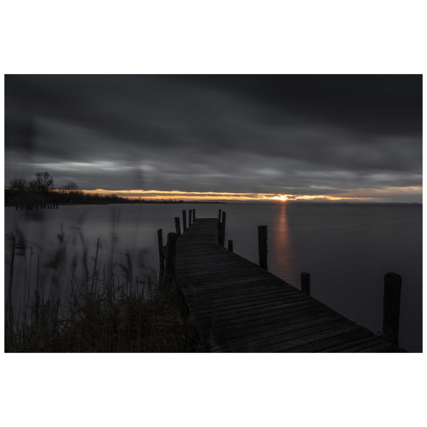Empty docks carry their own stories. Once a summer playground for kitesurfers chasing Pannonian winds, this November evening belongs to solitude and the slow fade of daylight beneath heavy Austrian skies. Here at the edge of Central Europe&rsquo;s we