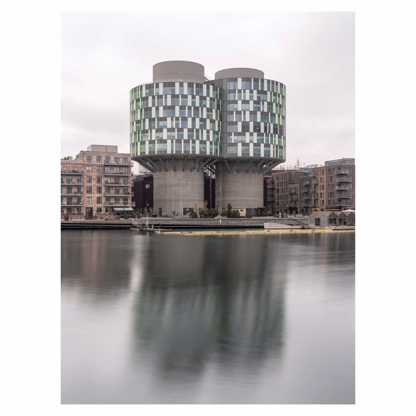 Built in 1979 to store cement, the Portland Towers spent decades as silent industrial monuments on Copenhagen&rsquo;s waterfront. Today, 13,000 square meters of glass wrapped offices float 24 meters above the harbor, cantilevered from the raw concret