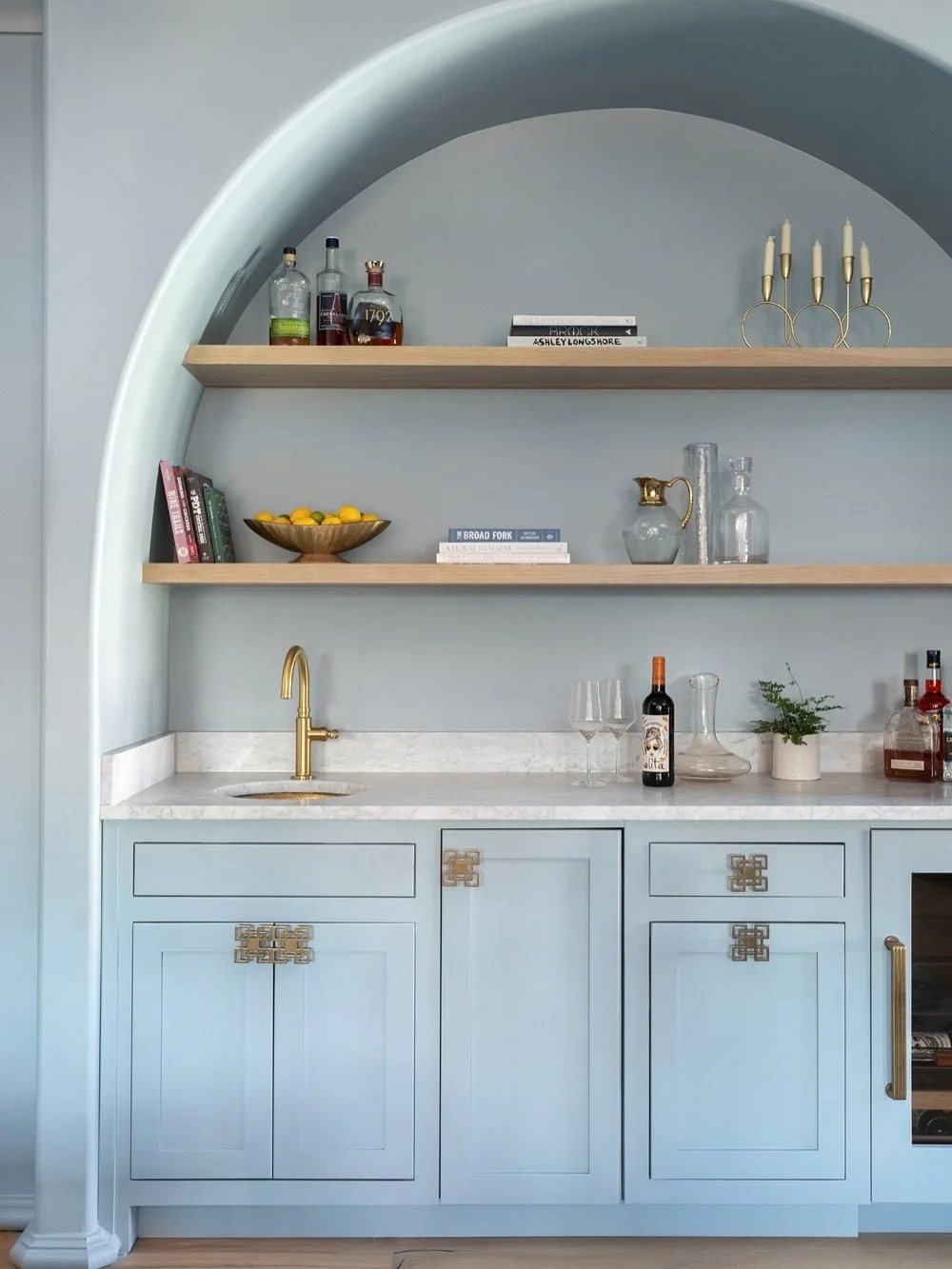 In the rec room of this Lake Oconee cottage, a hammered brass sink and open shelving make entertaining easy, while arches and blue tones echo design details found throughout the home.
Photography: @heidiface 
@southernluxuryhomes