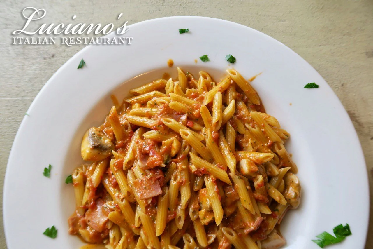 Penne All&aacute; Luciano - Luciano's own recipe. One of our specialties with prosciutto Cotto, mushrooms, cream and a touch of pesto and tomato sauce!