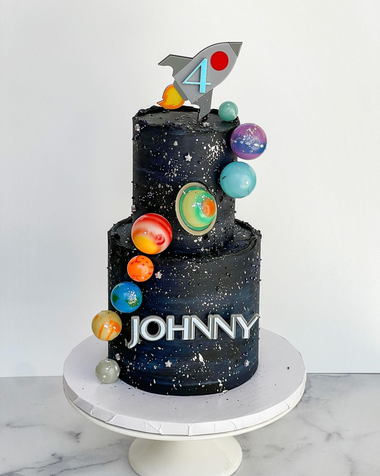 Space themes have been SO popular this past year! 🚀

Two Tier 4&rdquo; &amp; 6&rdquo; three layer funfetti cake with oreo buttercream filling, galaxy vanilla buttercream exterior, @floraldust_ layered acrylic rocketship topper &amp; layered acrylic 