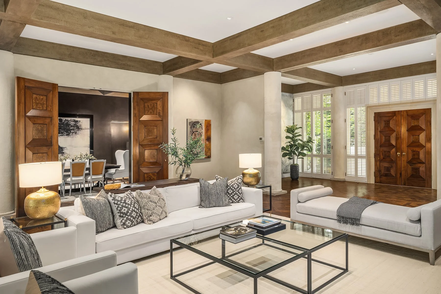 Lush green lawn with trees, a house partially visible, and four empty chairs facing the water, with a view of the ocean at sunset.