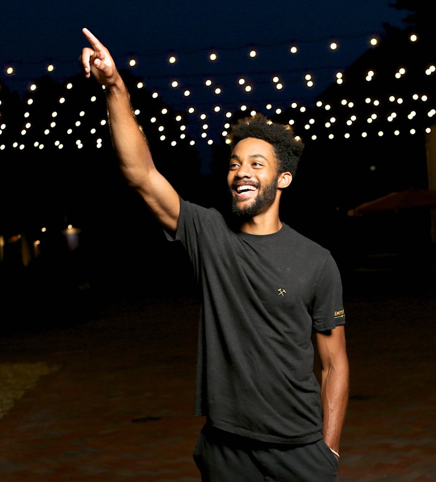 Model showcasing a black hemp shirt with vibrant party lights in the background